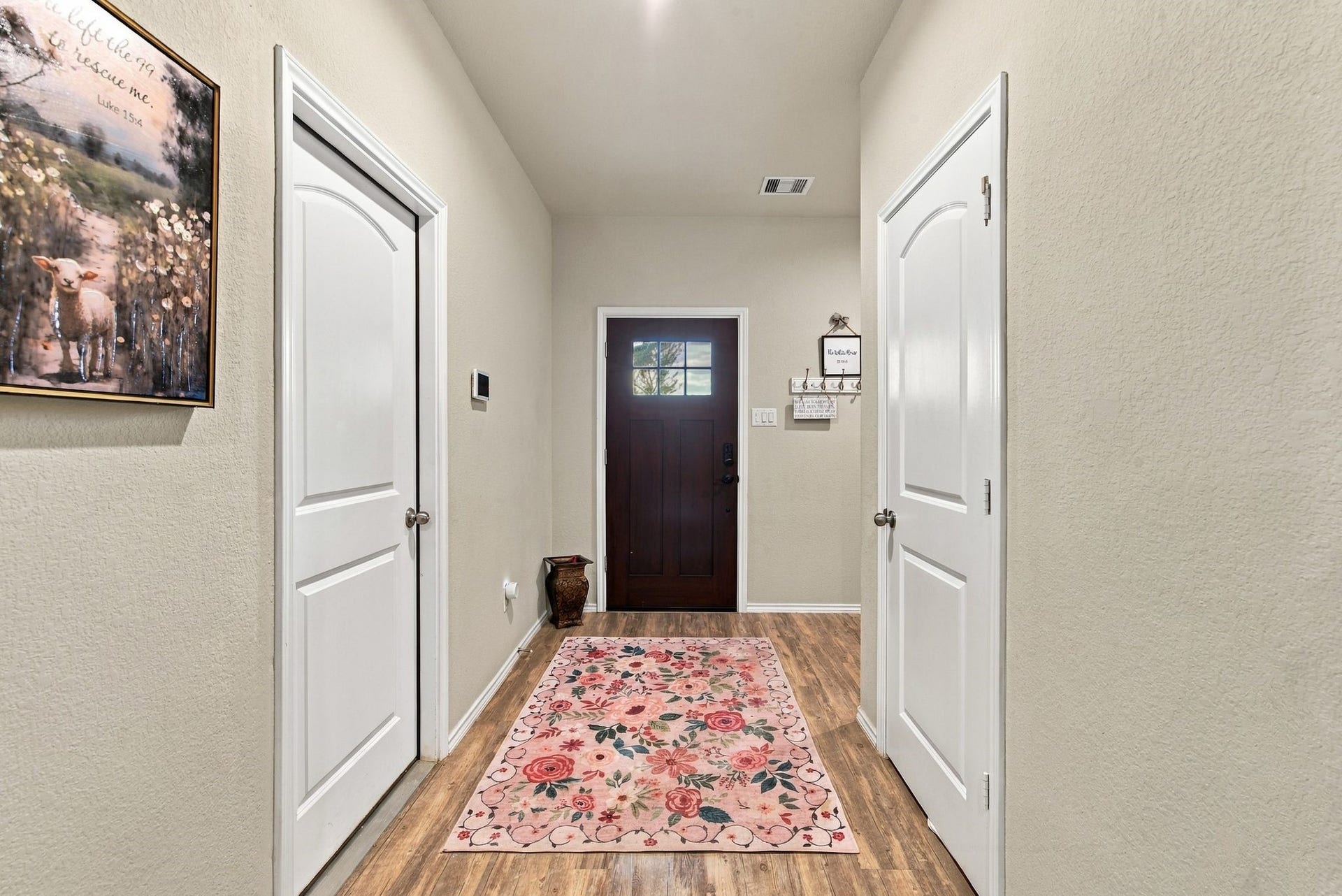11371 Dawn Beach Lane, Conroe, TX 77304 Inviting entryway featuring a warm wood door, elegant floral rug, and stylish decor, complemented by light walls and wood flooring.