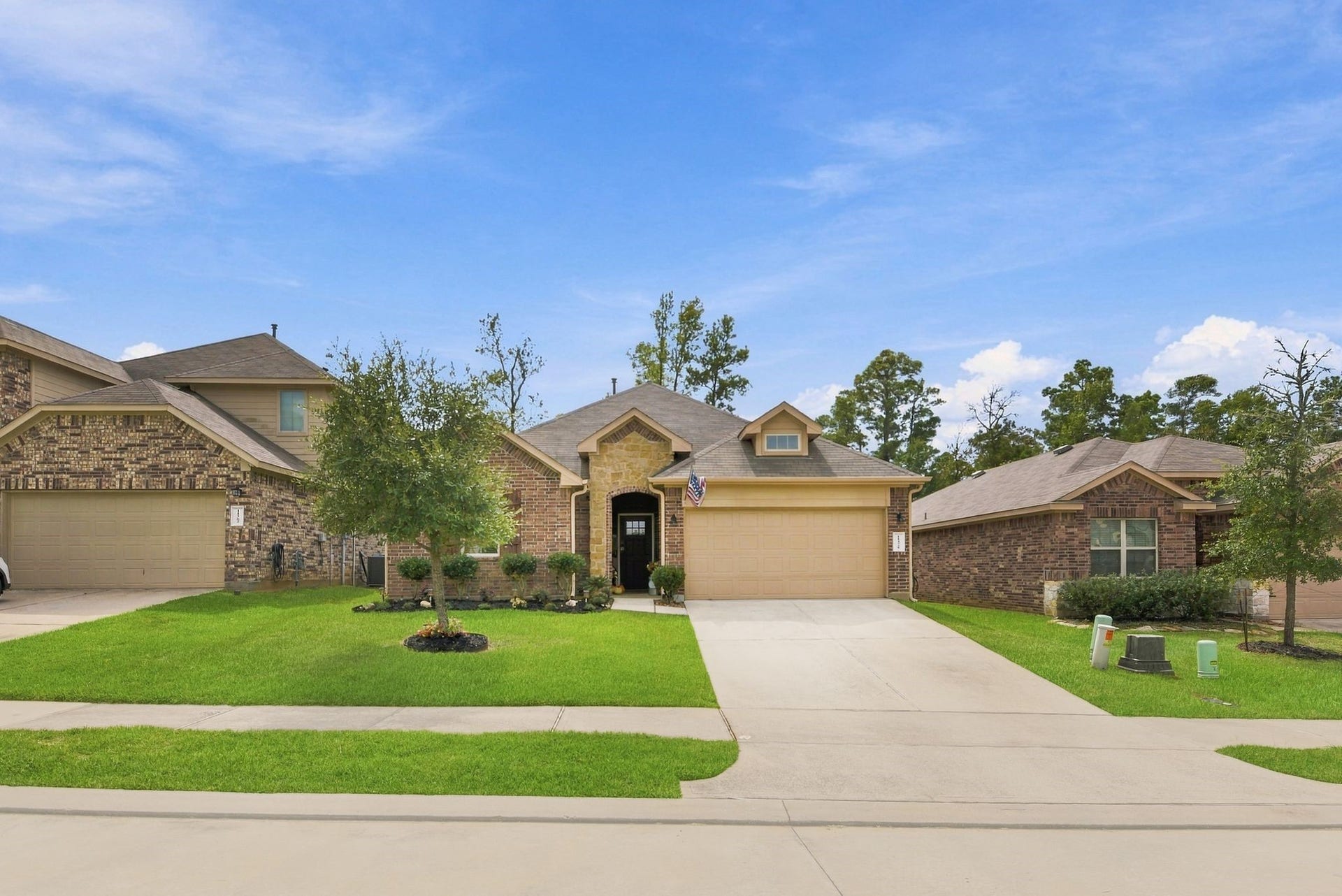 11371 Dawn Beach Lane, Conroe, TX 77304 Charming single-story brick home with a welcoming front porch, manicured lawn, and a spacious driveway in a peaceful neighborhood setting.