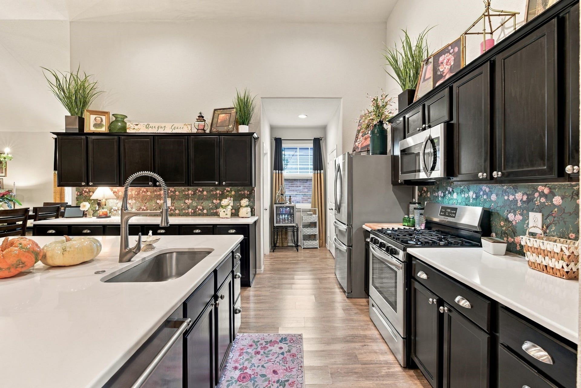 11371 Dawn Beach Lane, Conroe, TX 77304 Charming kitchen with elegant dark cabinetry, modern stainless steel appliances, and a stylish floral backsplash, creating a warm and inviting atmosphere.