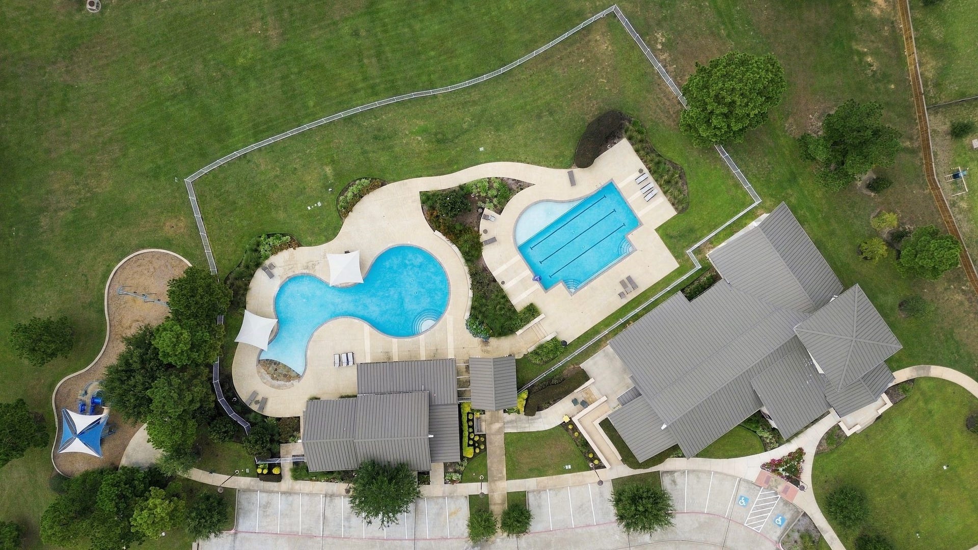 11371 Dawn Beach Lane, Conroe, TX 77304 Expansive recreational area featuring two large swimming pools, lush green lawns, and a spacious clubhouse, perfect for relaxation and outdoor activities.