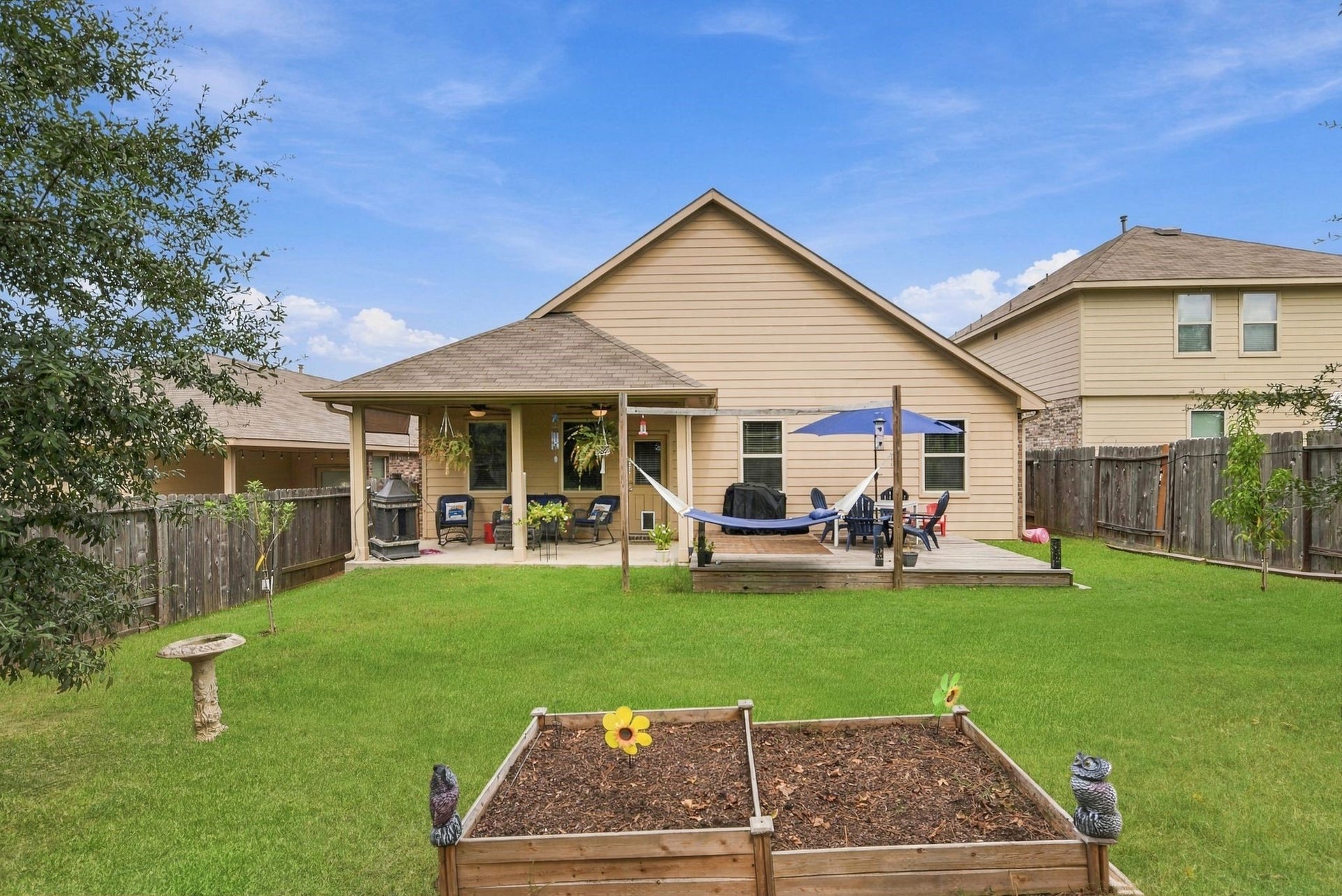 11371 Dawn Beach Lane, Conroe, TX 77304 Charming backyard with a covered patio, perfect for relaxation, featuring a hammock and outdoor seating. The spacious lawn includes a raised garden bed, ideal for gardening enthusiasts.