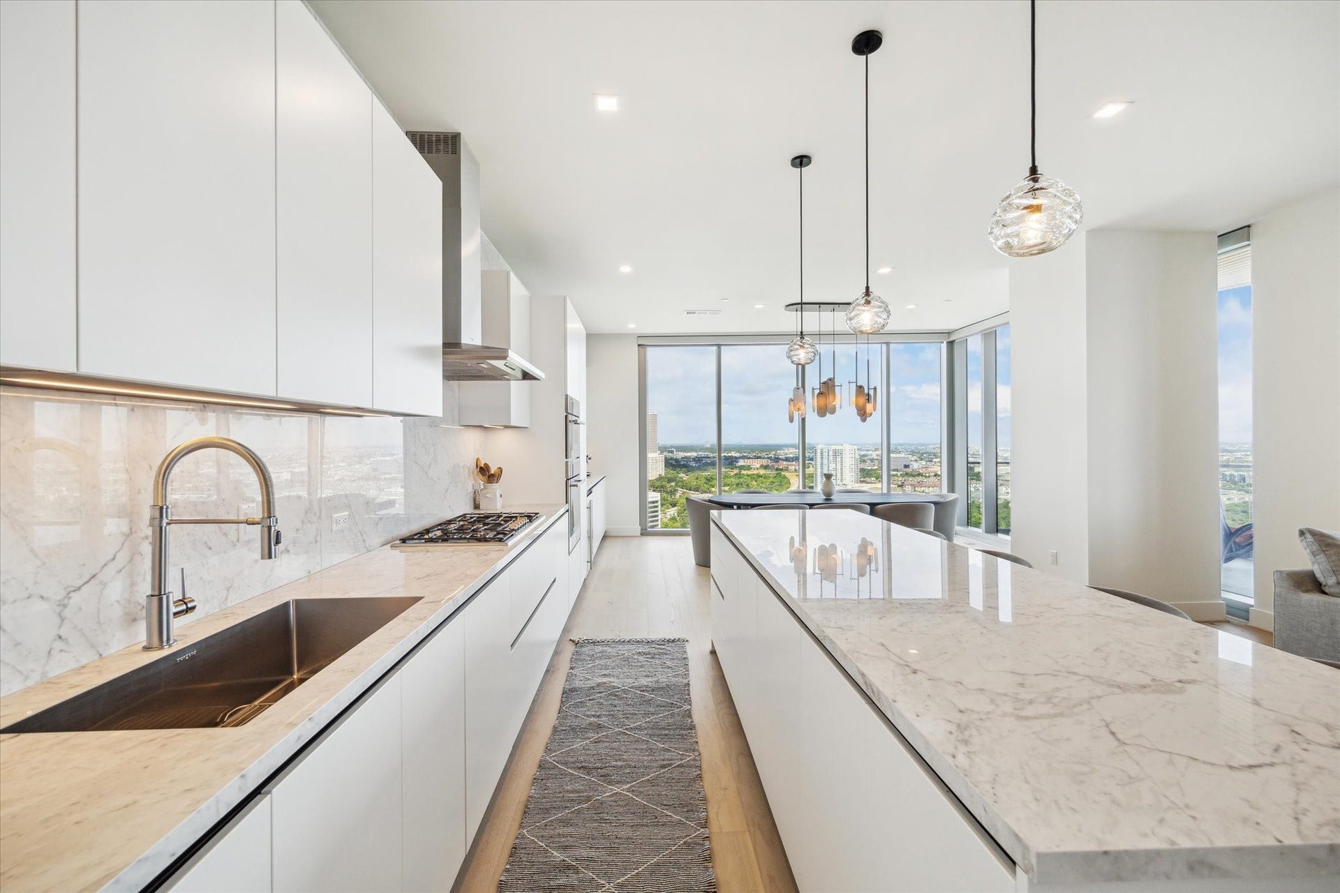 1711 Allen Parkway, #2601, Houston, TX 77019 Pendant lighting handcrafted by Siemon and Salazar accent the porcelain countertops in the large kitchen.
