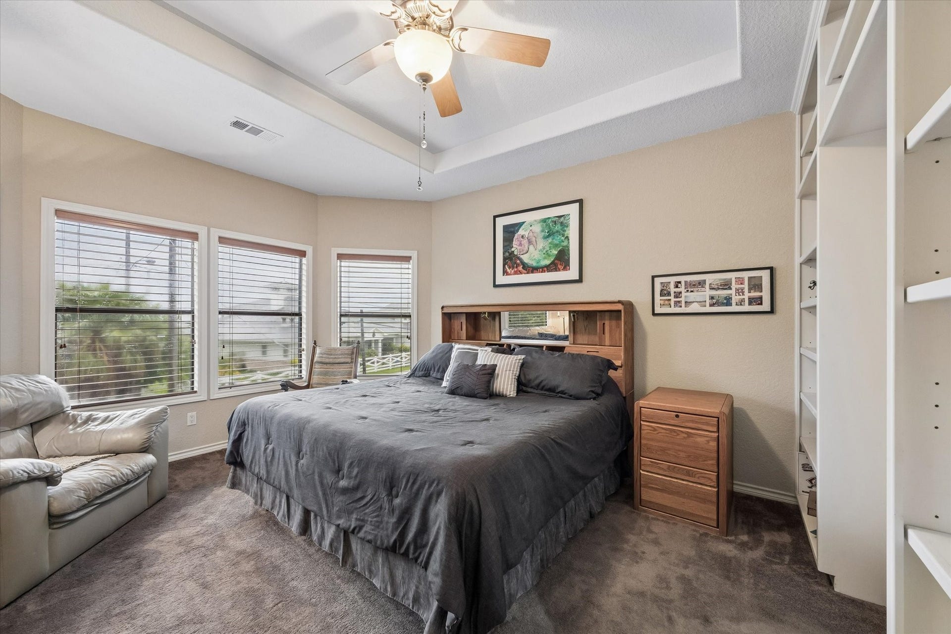 3040 Bayshore Drive, Bacliff, TX 77518 Spacious primary bedroom with tray ceiling, ceiling fan, and abundant natural light from multiple windows. Generous layout accommodates large furnishings with comfortable seating area.