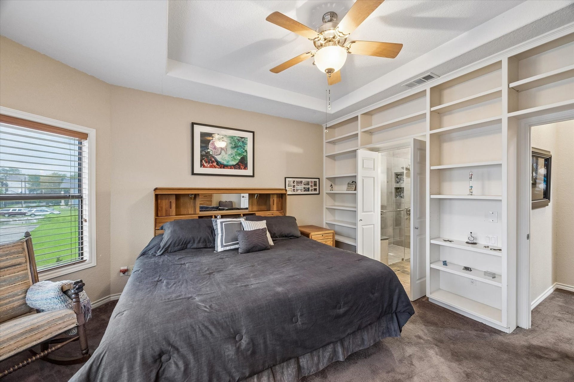 3040 Bayshore Drive, Bacliff, TX 77518 Primary bedroom featuring tray ceiling, ceiling fan, and custom built-in shelving. Direct access to the en-suite bath enchances functionaility and storage.