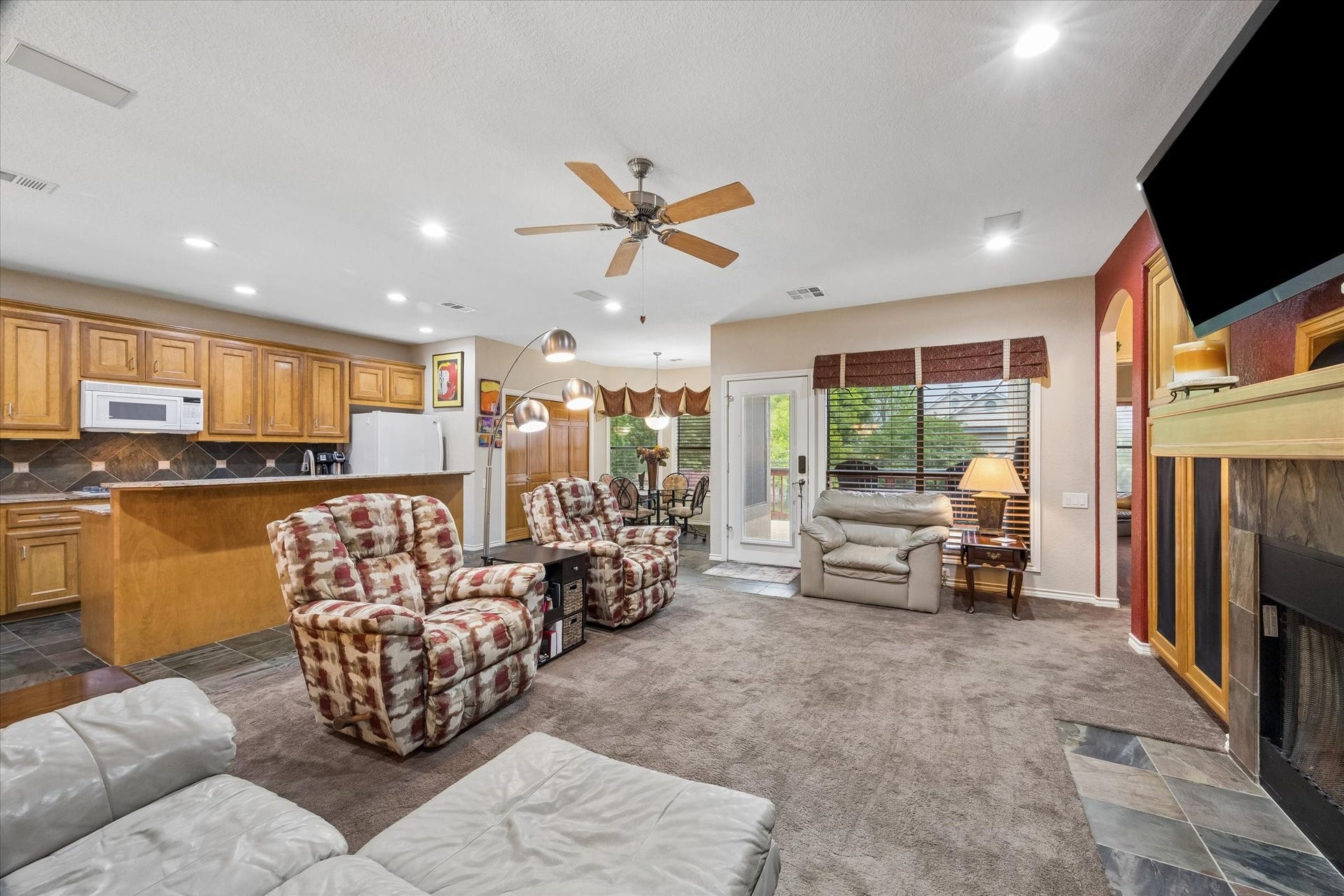 3040 Bayshore Drive, Bacliff, TX 77518 Open living area with fireplace and built-in cabinetry, featuring direct access to the covered upper deck. Seamless connection to the kitchen and dining area enhances flow for everyday living and entertaining.