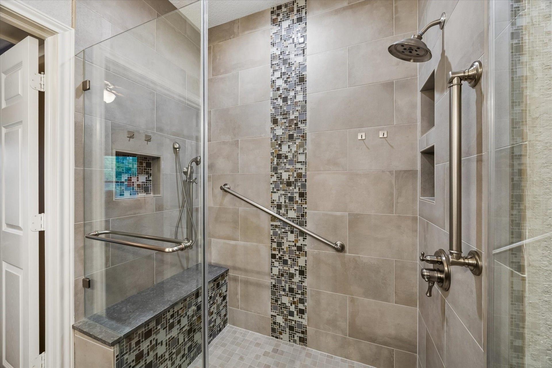 3040 Bayshore Drive, Bacliff, TX 77518 Walk-in shower with glass enclosure, tile surround, and decorative accent strip. Features built-in bench seating, recesses niches, and grab bars for added functionality.