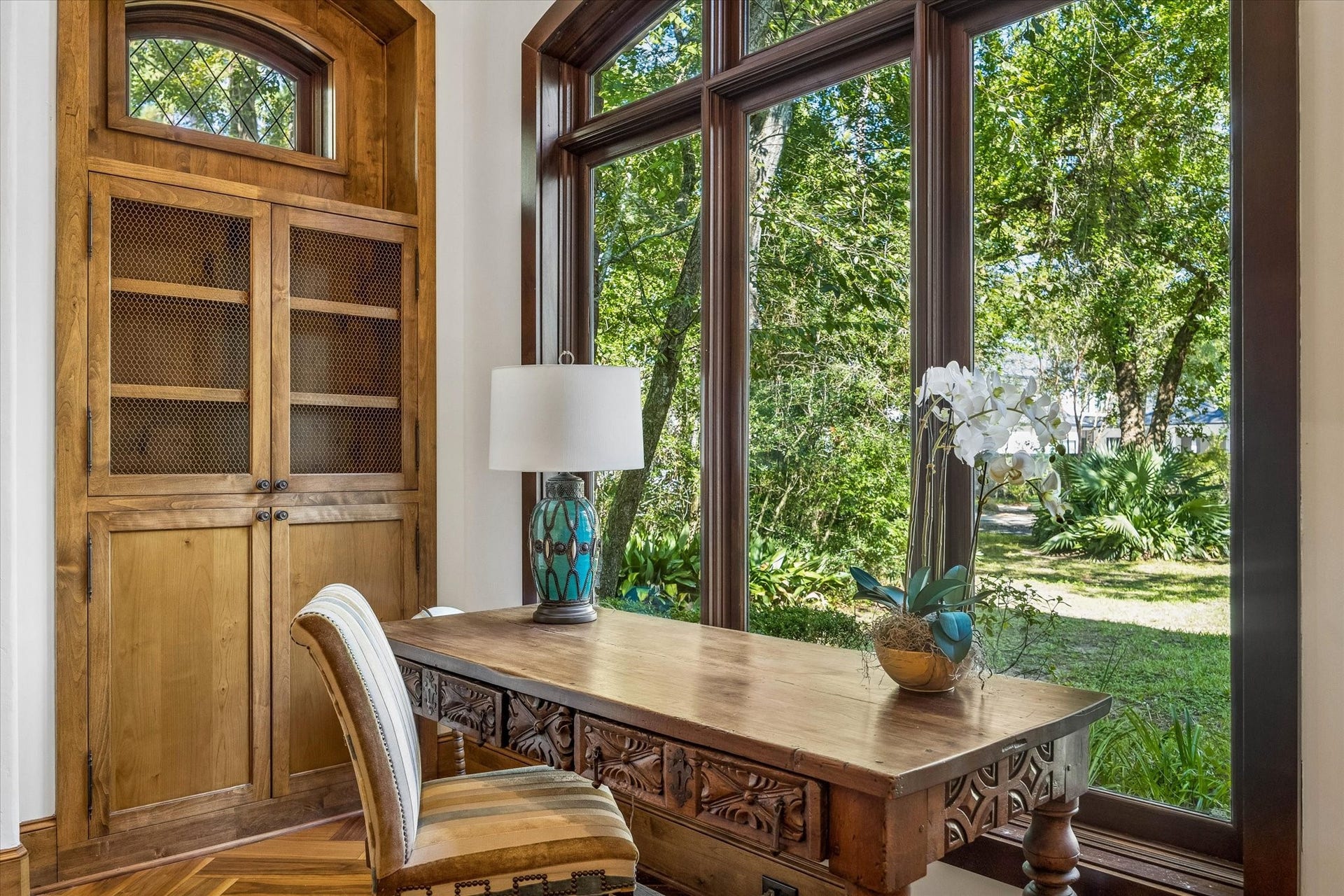 34 Liberty Bell Circle, Bunker Hill Village, TX 77024 A quiet corner of the living room overlooking the front grounds, where expansive arched windows fill the space with natural light and custom wood cabinetry adds warmth and character.