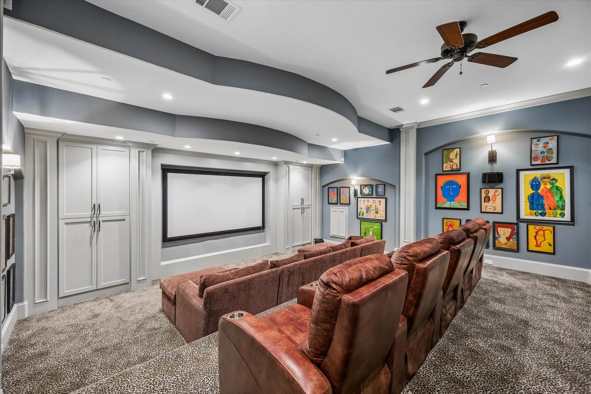 34 Liberty Bell Circle, Bunker Hill Village, TX 77024 The upstairs media room is designed for movie nights and entertaining, featuring a large projection screen, tiered seating, custom built-ins, and distinctive curved ceiling details.