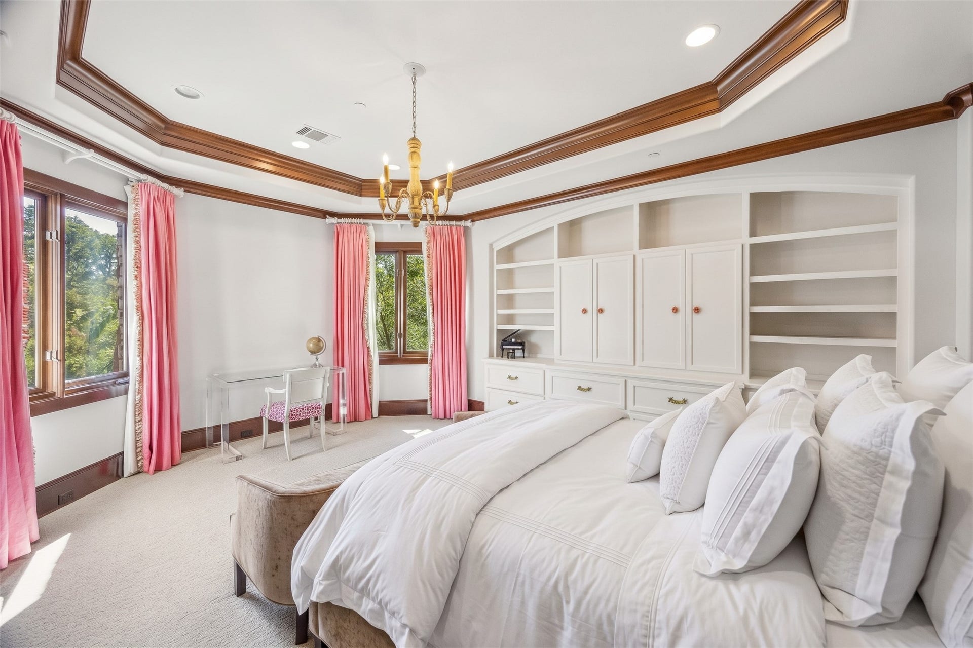 34 Liberty Bell Circle, Bunker Hill Village, TX 77024 A bright upstairs bedroom with custom built-in shelving and cabinetry, detailed crown molding, and windows offering treetop views.