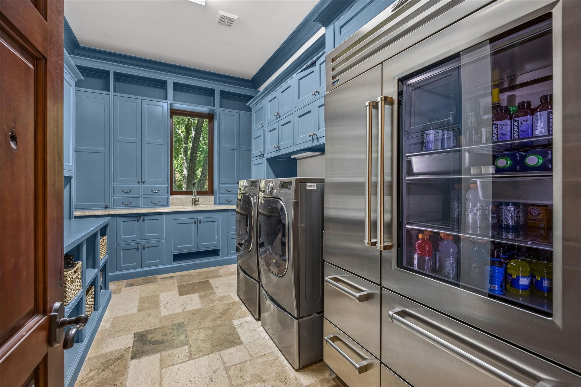 34 Liberty Bell Circle, Bunker Hill Village, TX 77024 The main utility room combines function and style with custom blue cabinetry, generous storage, a utility sink, space for full-size laundry appliances, and additional refrigeration.