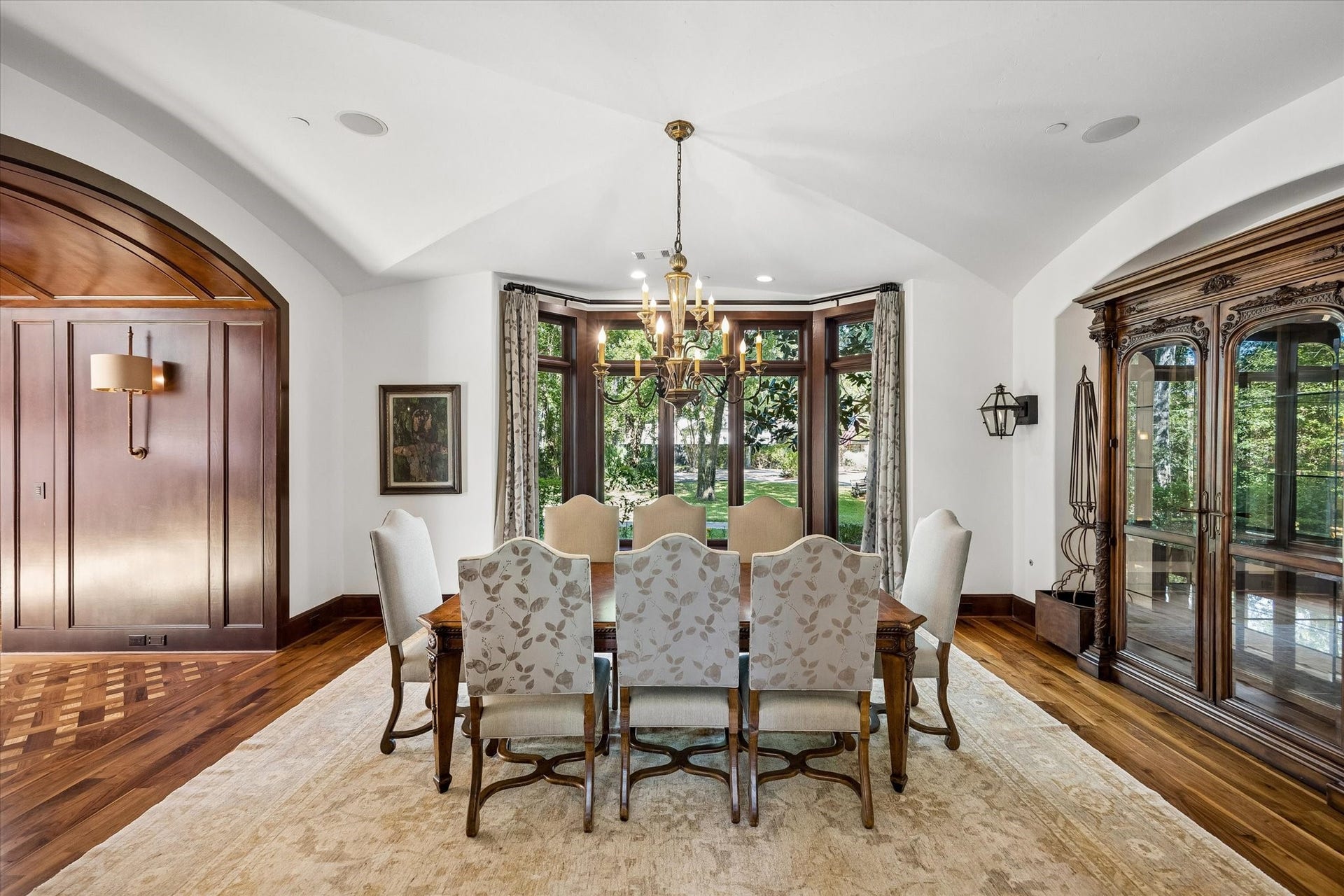 34 Liberty Bell Circle, Bunker Hill Village, TX 77024 The formal dining room offers a beautiful setting for gatherings, with a graceful vaulted ceiling, rich wood detailing, hardwood floors, and a wall of windows overlooking the front grounds.