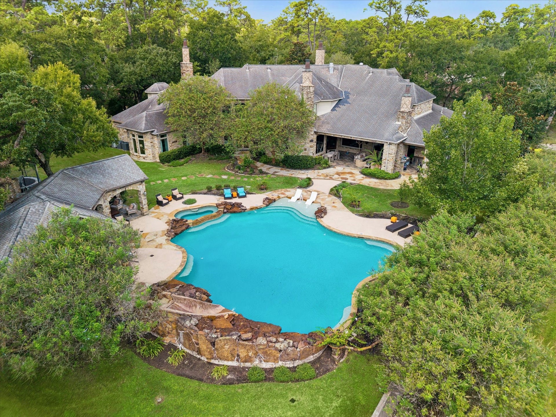 34 Liberty Bell Circle, Bunker Hill Village, TX 77024 Expansive backyard featuring a resort-style pool with integrated spa, stone waterfalls, generous patio spaces, and multiple covered outdoor living areas ideal for entertaining.