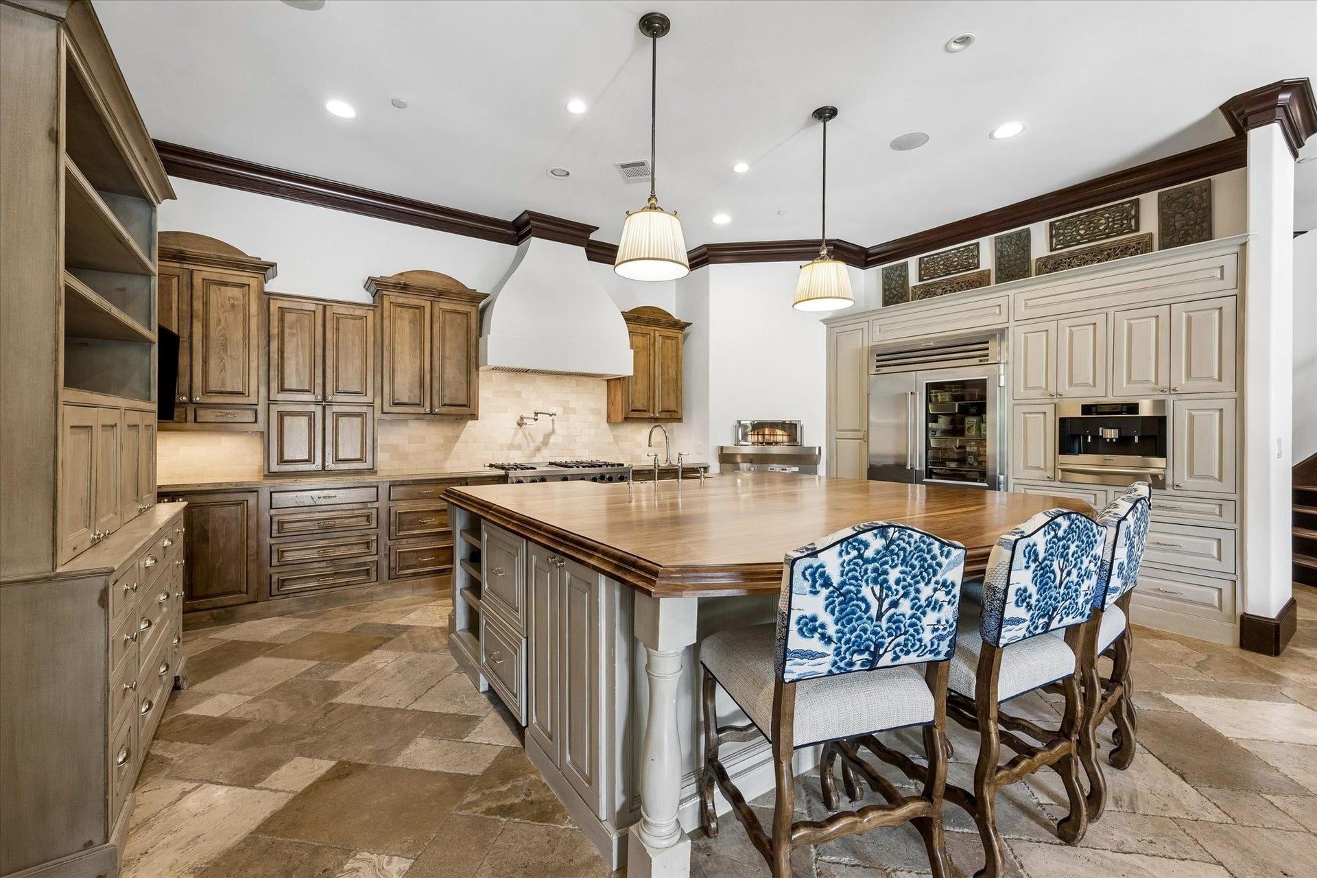 34 Liberty Bell Circle, Bunker Hill Village, TX 77024 A different perspective of the kitchen showcases the generous proportions, contrasting cabinetry, natural stone flooring, and decorative architectural details that give the space its distinctive character.