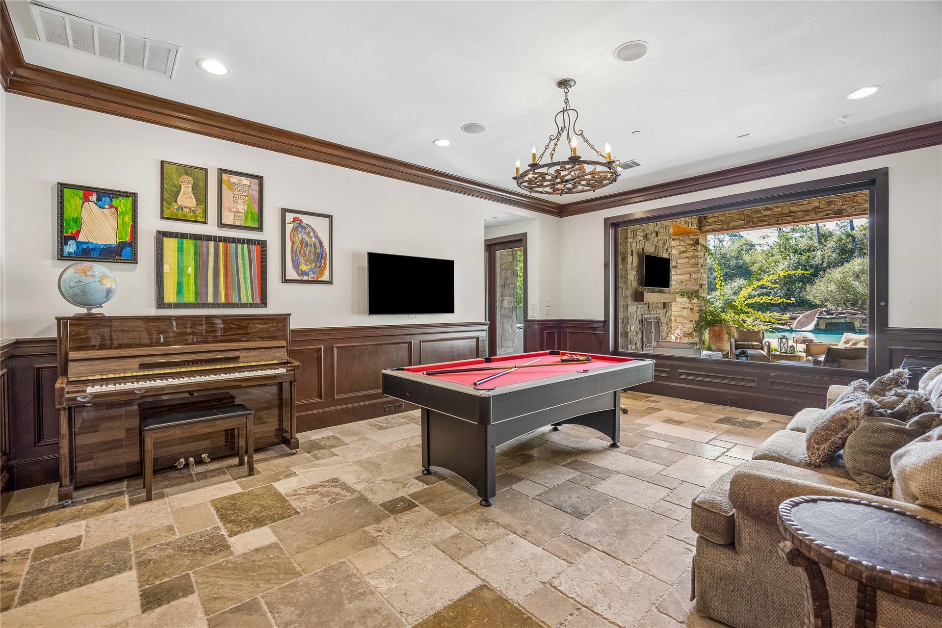 34 Liberty Bell Circle, Bunker Hill Village, TX 77024 The downstairs game room offers a spacious setting for recreation and entertaining, with stone flooring, rich wood wainscoting, and a large picture window overlooking the covered patio and pool.