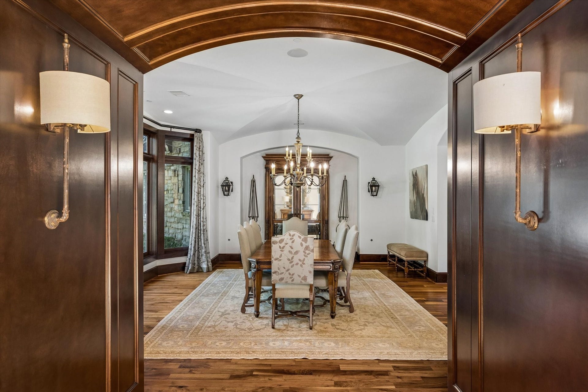 34 Liberty Bell Circle, Bunker Hill Village, TX 77024 An elegant transition into the formal dining room, where rich wood paneling and an arched entry open to a spacious room with a graceful barrel-vaulted ceiling, hardwood floors, and natural light.