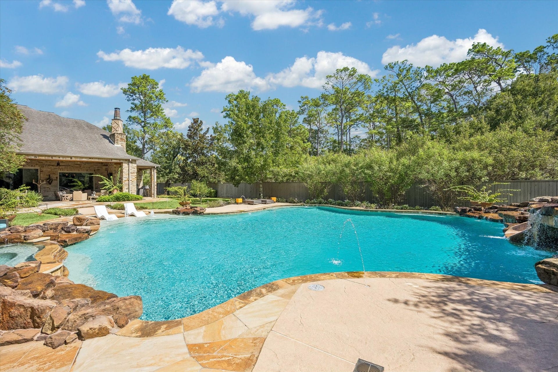 34 Liberty Bell Circle, Bunker Hill Village, TX 77024 An impressive resort-style pool takes center stage in the backyard, offering generous space for swimming and relaxation with cascading waterfalls, fountains, and expansive surrounding patios.