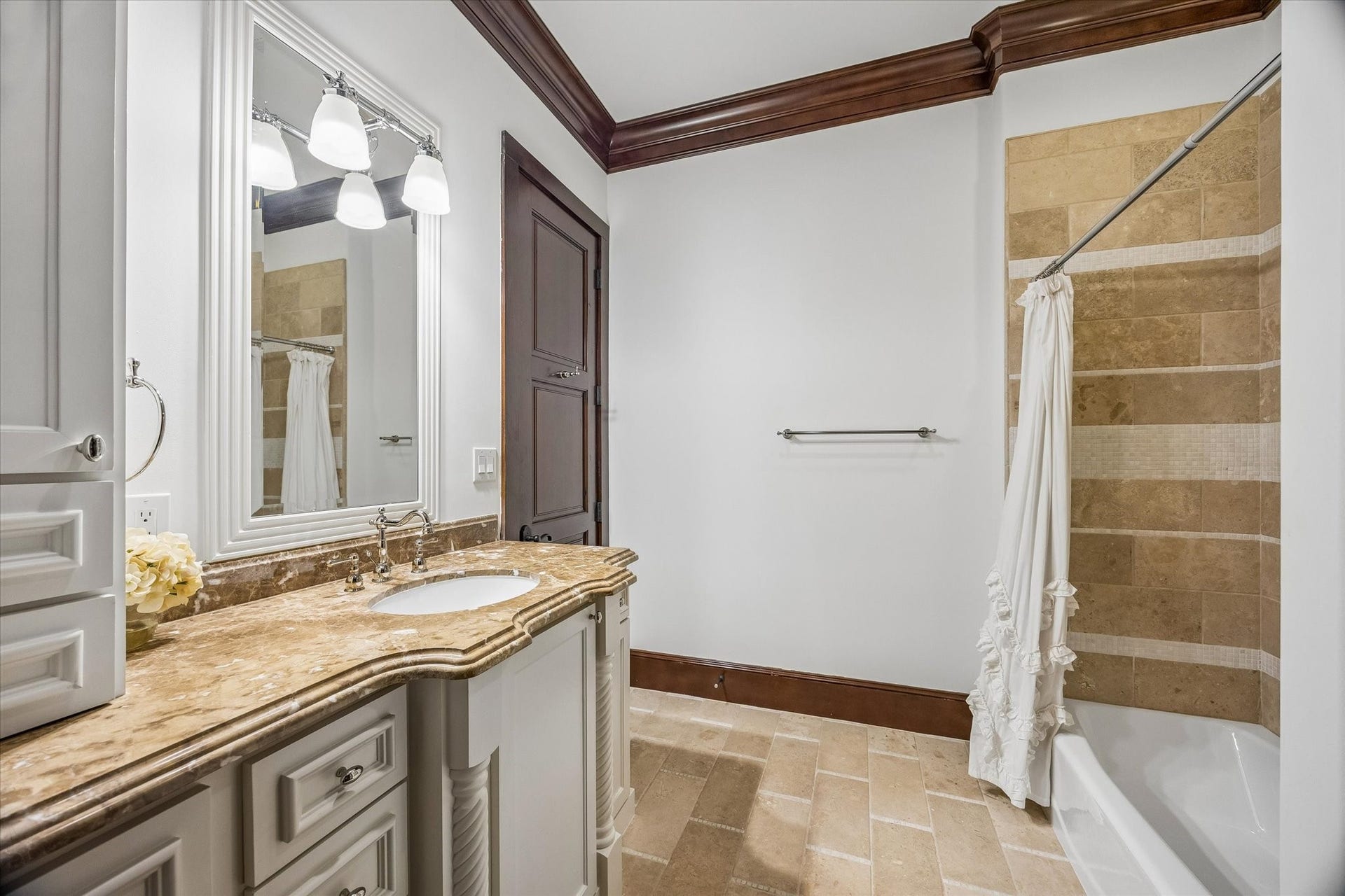 34 Liberty Bell Circle, Bunker Hill Village, TX 77024 The adjoining bath features a stone-topped vanity with custom cabinetry, natural stone flooring, and a tub and shower combination with decorative tile accents.