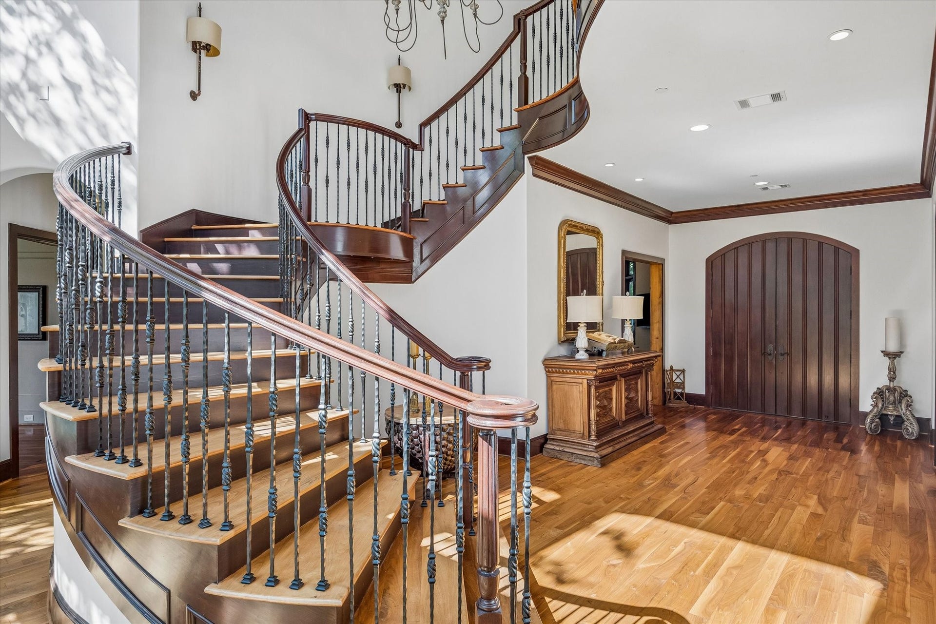 34 Liberty Bell Circle, Bunker Hill Village, TX 77024 Grand two-story entry featuring a sweeping curved staircase with wood treads, wrought iron balusters, rich wood detailing, hardwood floors, and arched double entry doors.