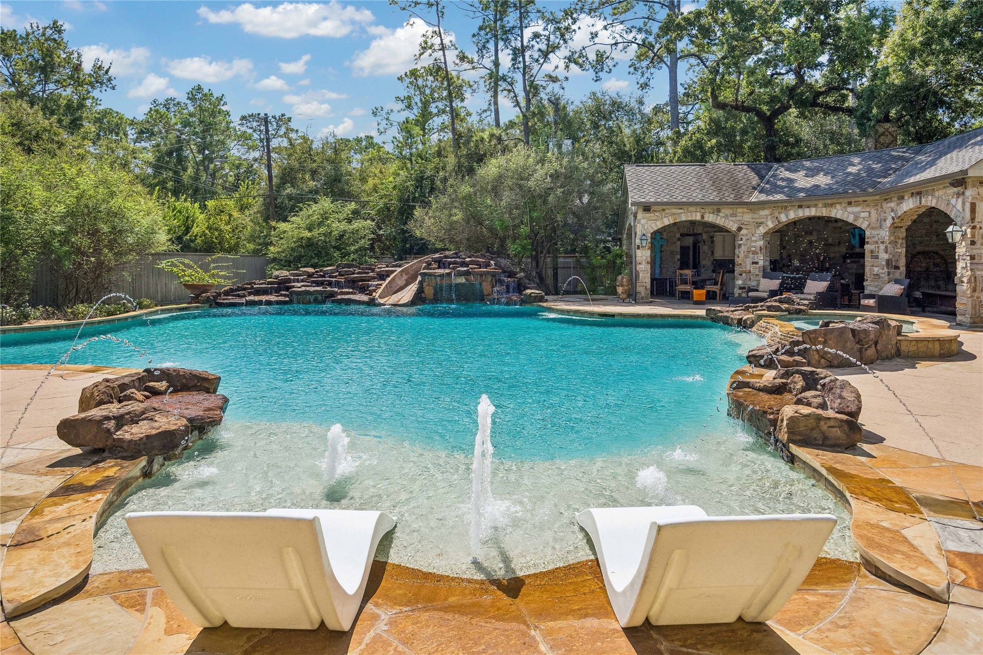 34 Liberty Bell Circle, Bunker Hill Village, TX 77024 The pool's custom design includes a stone waterfall, waterslide, and multiple water features, with a covered outdoor pavilion just steps away.