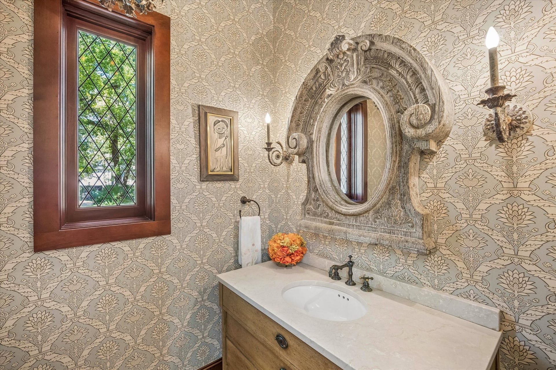 34 Liberty Bell Circle, Bunker Hill Village, TX 77024 The formal powder room features elegant patterned wallcovering, a stone-topped vanity, leaded glass window, and traditional architectural details.
