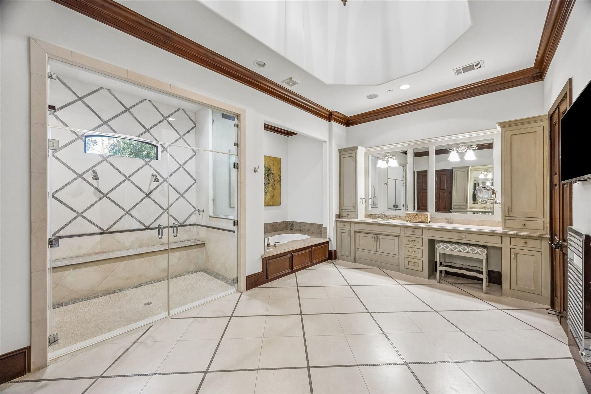34 Liberty Bell Circle, Bunker Hill Village, TX 77024 The spacious primary bath offers a spa-like setting with soaring ceilings, a soaking tub, custom cabinetry, a vanity area, and access to two incredible walk-in closets.