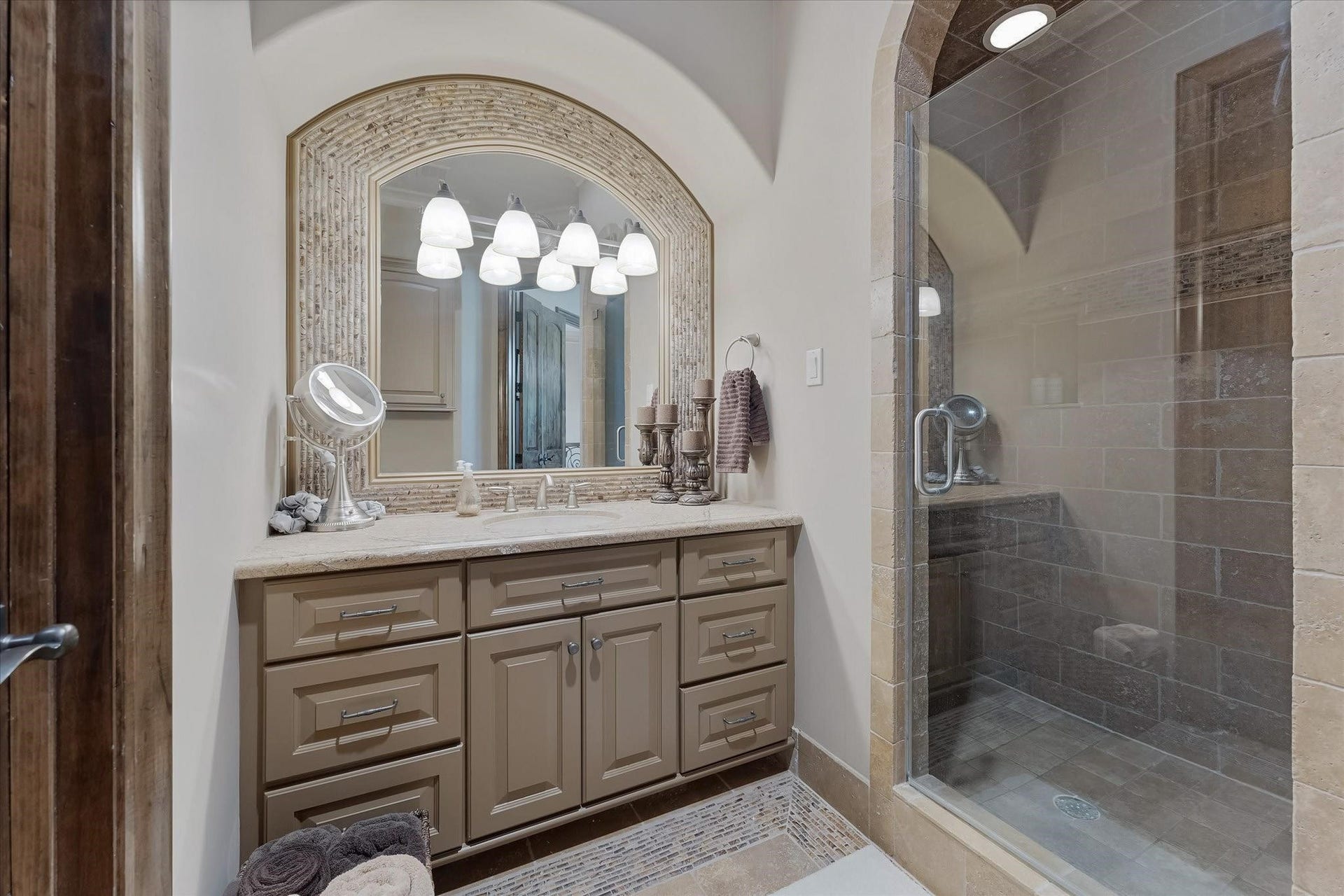 28322 Meadow Forest, Magnolia, TX 77355 Guest bedroom ensuite #1 on the second floor.
Dual Adler wood doors lead to the Ensuite bathroom with custom tile flooring with intricate patterns, a shower with a built-in bench, and a Granite countertop vanity with Custom framed mirror. Walk-in Closet with built-in and door jamb Light Switch.