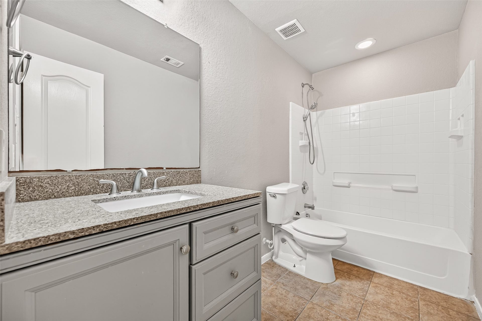 19707 Dayton Springs Drive, Cypress, TX 77429 Modern bathroom featuring a sleek granite countertop, elegant fixtures, and a pristine white bathtub with shower.