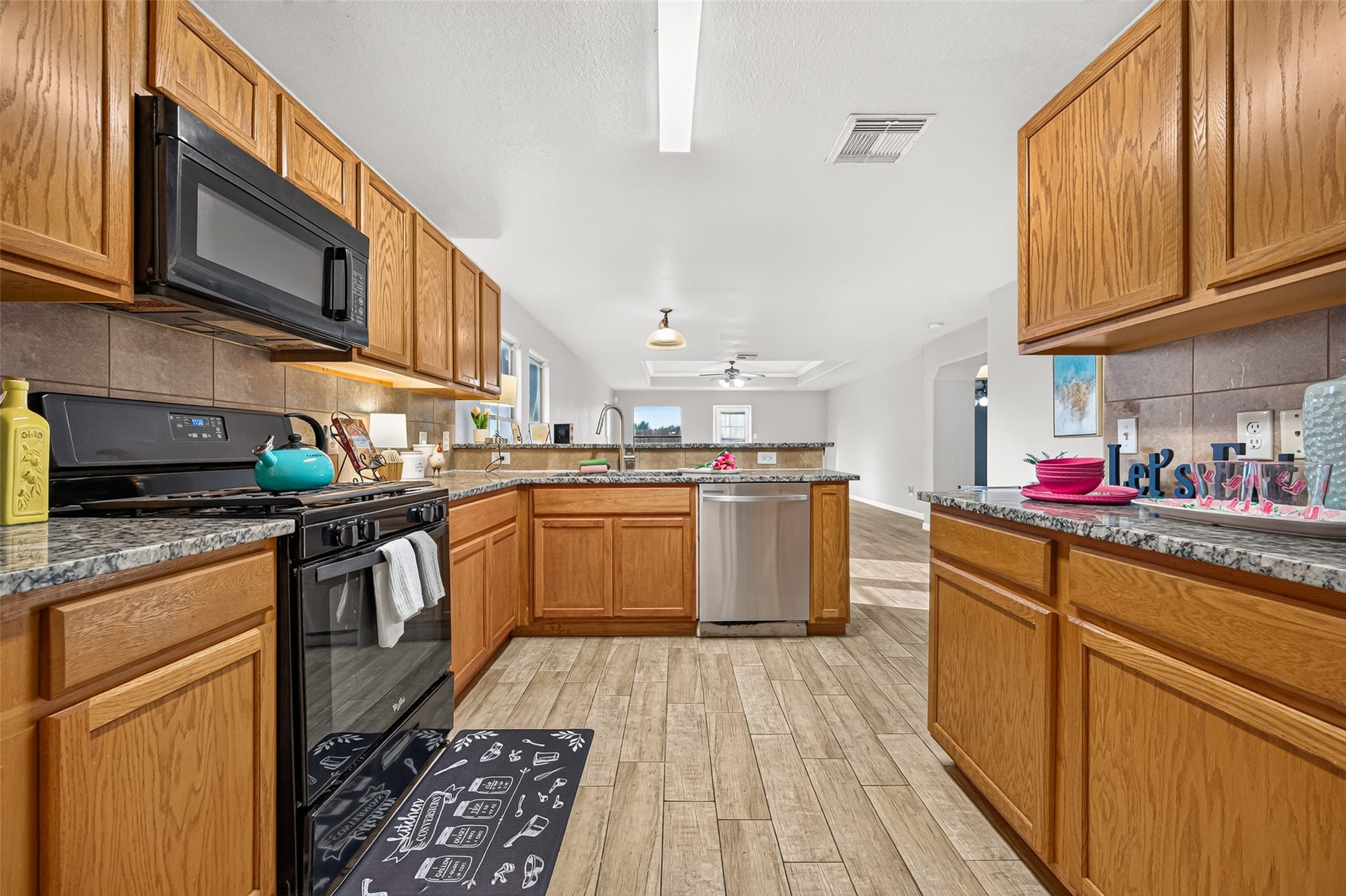 19707 Dayton Springs Drive, Cypress, TX 77429 Spacious kitchen with warm wood cabinetry, granite countertops, and stainless steel appliances, seamlessly flowing into an open-concept living area.