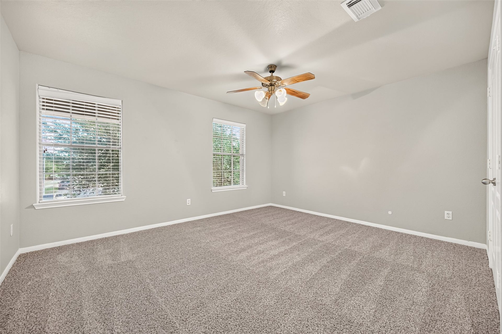 19707 Dayton Springs Drive, Cypress, TX 77429 Spacious bedroom with fresh neutral paint, plush carpet, and abundant natural light from large windows.