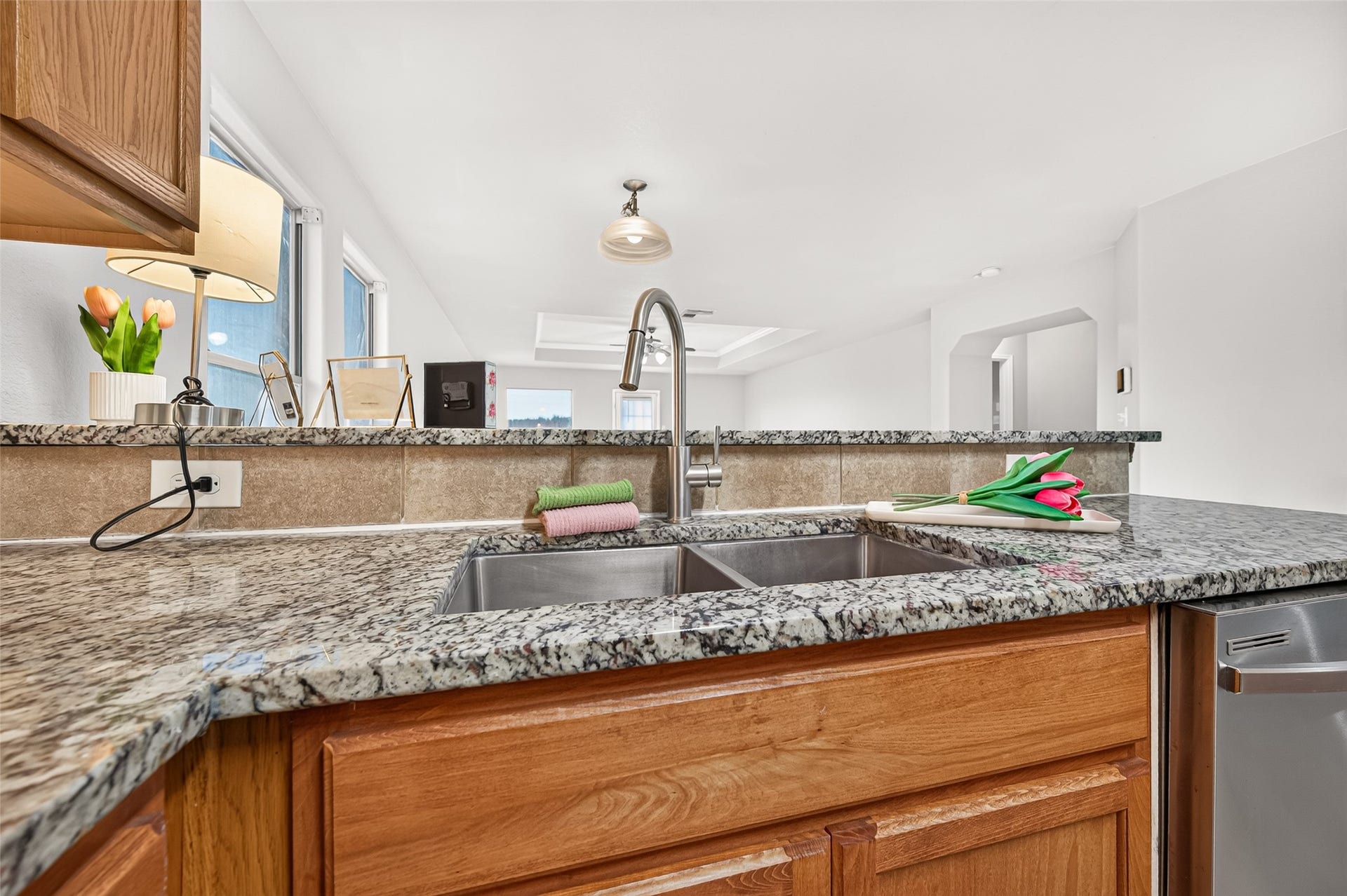 19707 Dayton Springs Drive, Cypress, TX 77429 Spacious kitchen with granite countertops, stainless steel sink, and warm wooden cabinetry, offering a bright and inviting space for cooking and entertaining.