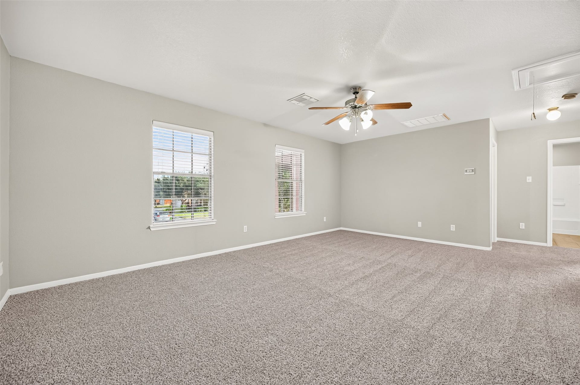19707 Dayton Springs Drive, Cypress, TX 77429 Spacious room with plush carpeting, neutral walls, and abundant natural light from large windows. Ceiling fan adds comfort and style. Perfect for a versatile living area or bedroom.