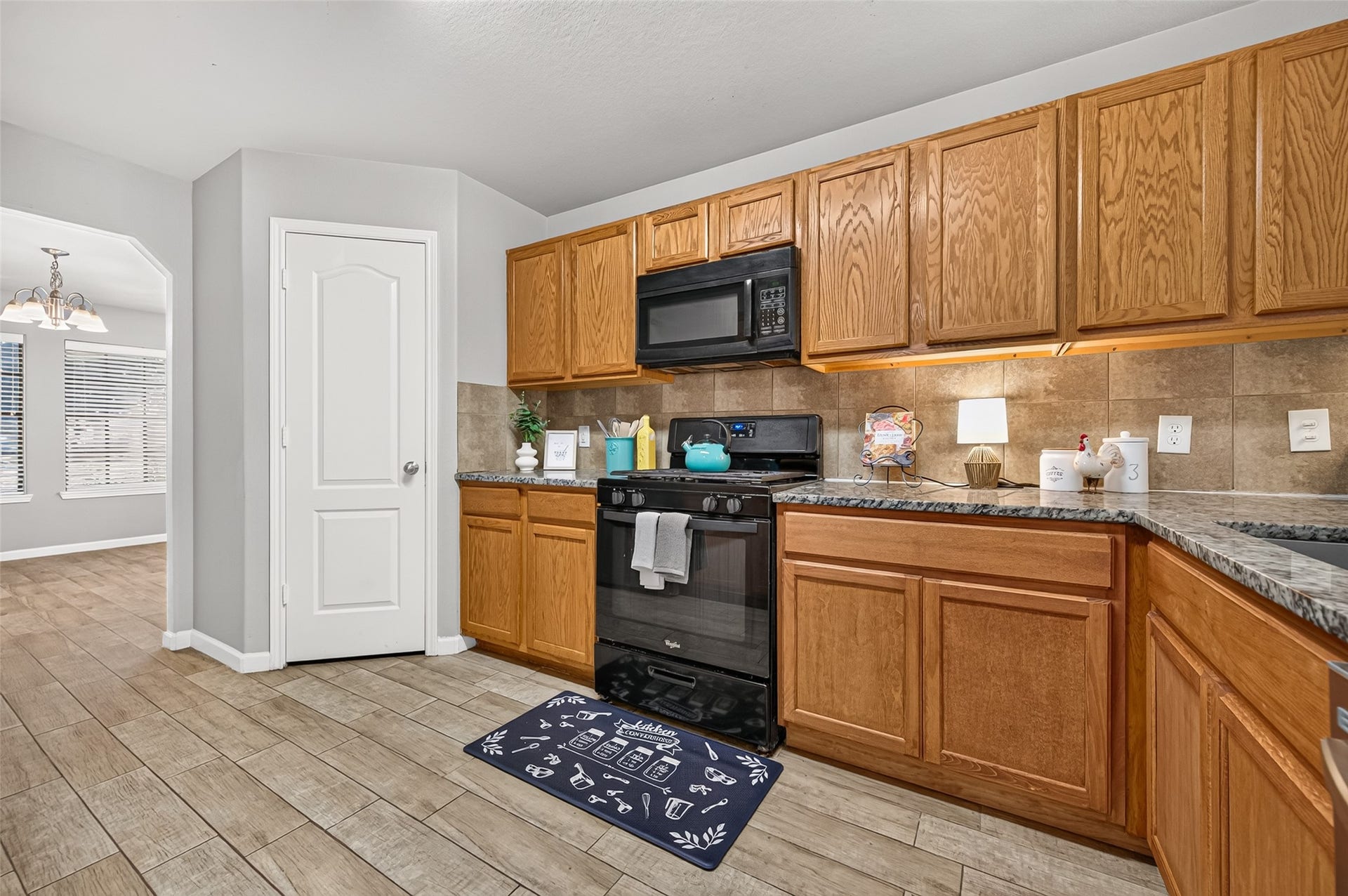 19707 Dayton Springs Drive, Cypress, TX 77429 Charming kitchen with warm wood cabinetry, granite countertops, and black appliances. The open layout flows into a bright dining area, perfect for entertaining.