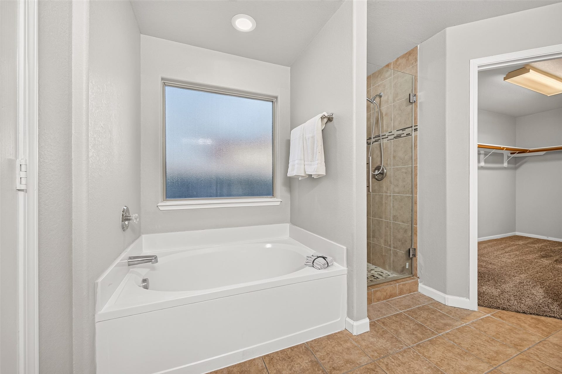 19707 Dayton Springs Drive, Cypress, TX 77429 Spacious bathroom with a relaxing soaking tub, separate tiled shower, and convenient access to a walk-in closet.