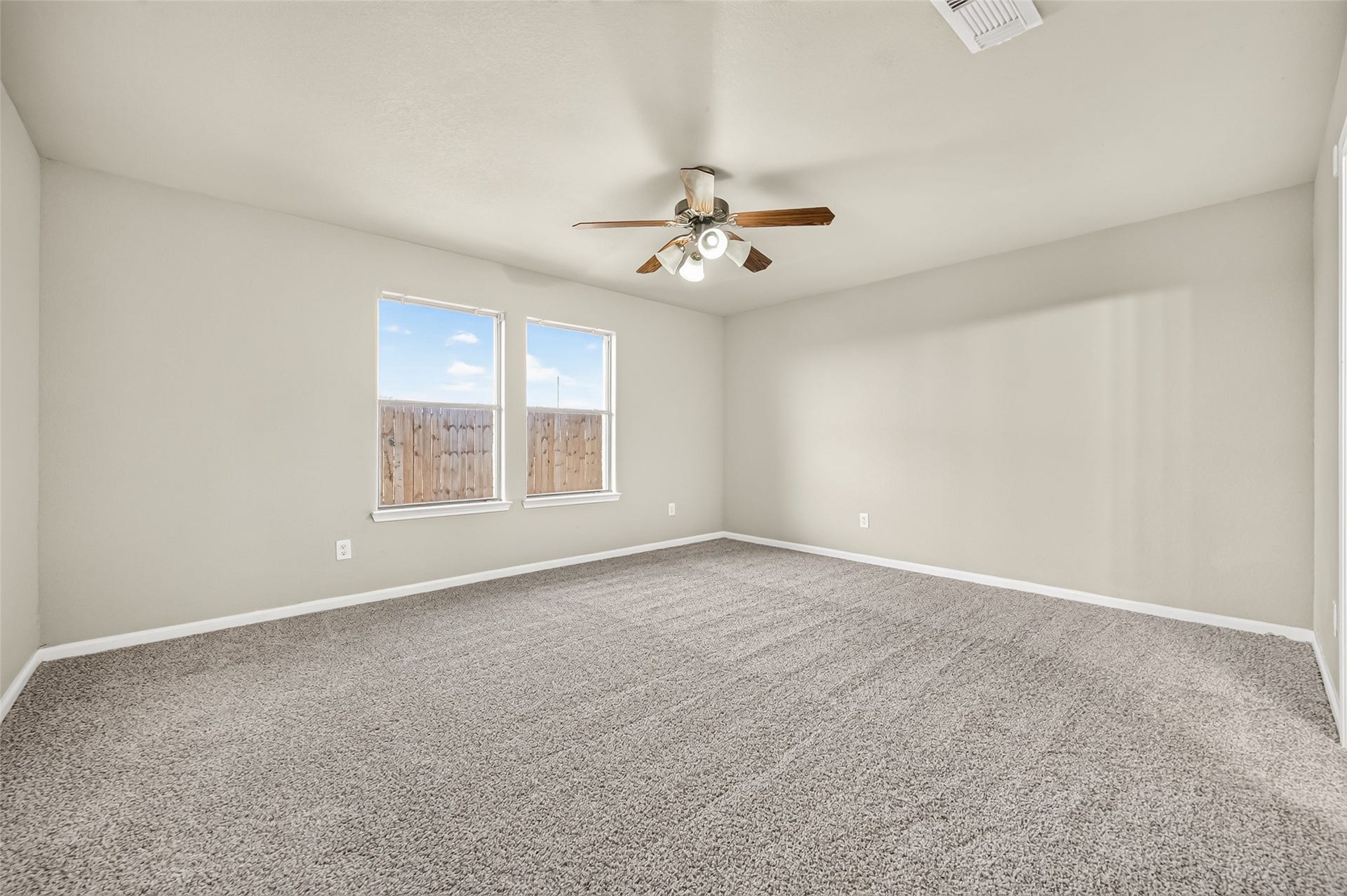 19707 Dayton Springs Drive, Cypress, TX 77429 Spacious bedroom with soft new carpeting, neutral walls, and abundant natural light from two large windows, complete with a ceiling fan for comfort.