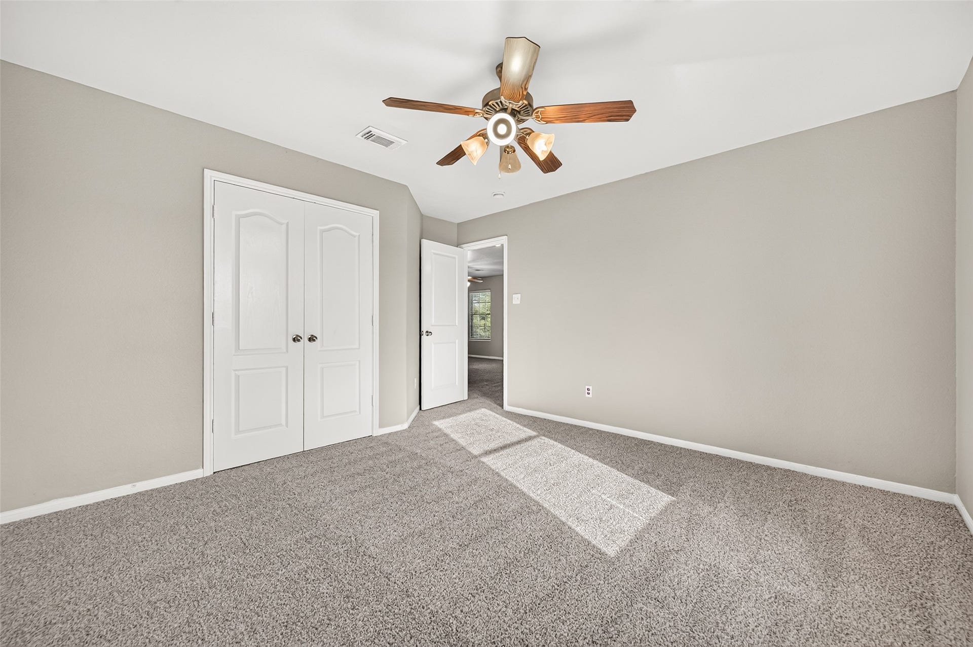 19707 Dayton Springs Drive, Cypress, TX 77429 Spacious bedroom with soft carpet flooring, neutral walls, and plenty of natural light, featuring a stylish ceiling fan and a double-door closet.