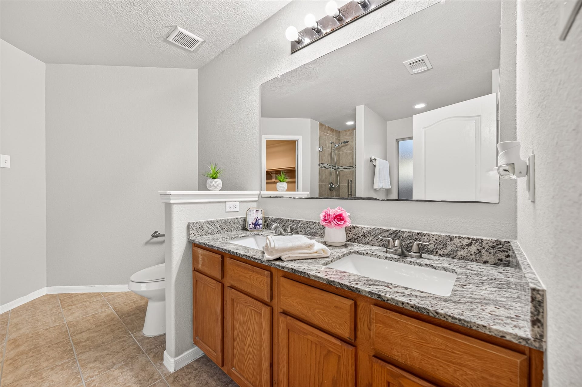 19707 Dayton Springs Drive, Cypress, TX 77429 Spacious primary bathroom featuring a dual-sink vanity with elegant granite countertops and ample storage, complemented by a large mirror.