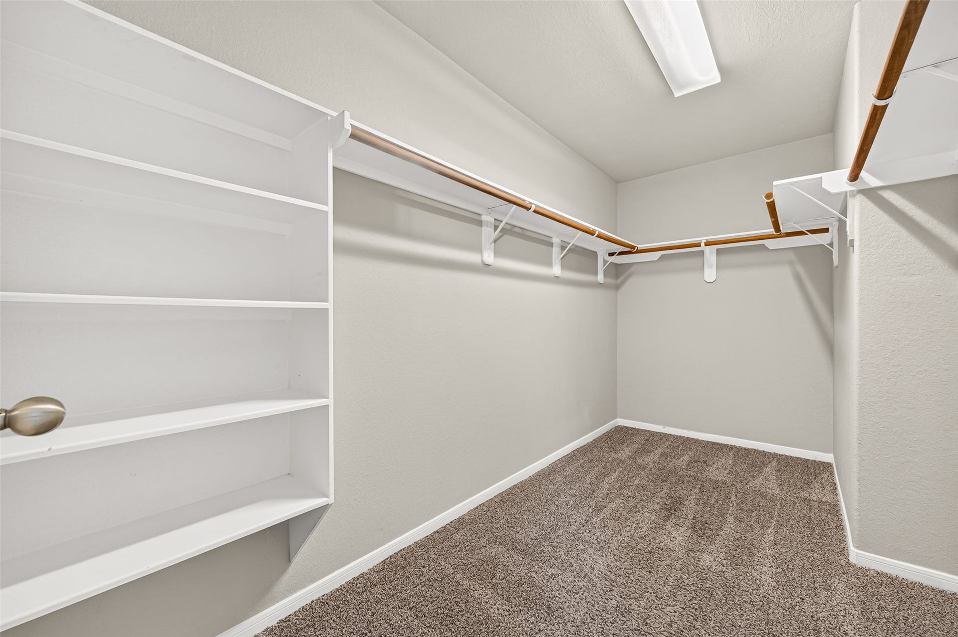 19707 Dayton Springs Drive, Cypress, TX 77429 Spacious walk-in closet with ample shelving and hanging space, complemented by soft carpet flooring and bright overhead lighting.