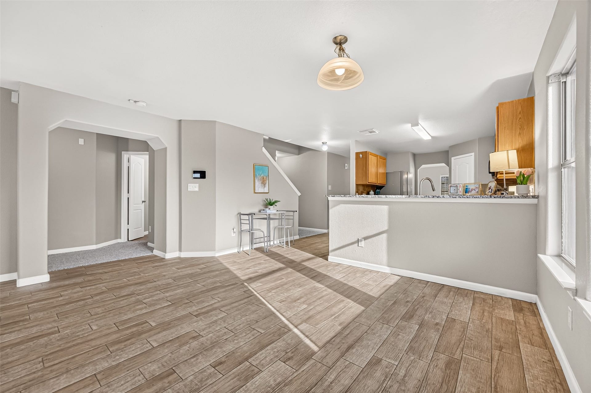 19707 Dayton Springs Drive, Cypress, TX 77429 Bright open-concept living space featuring modern wood-look flooring, kitchen with granite countertops, and ample natural light from large windows.