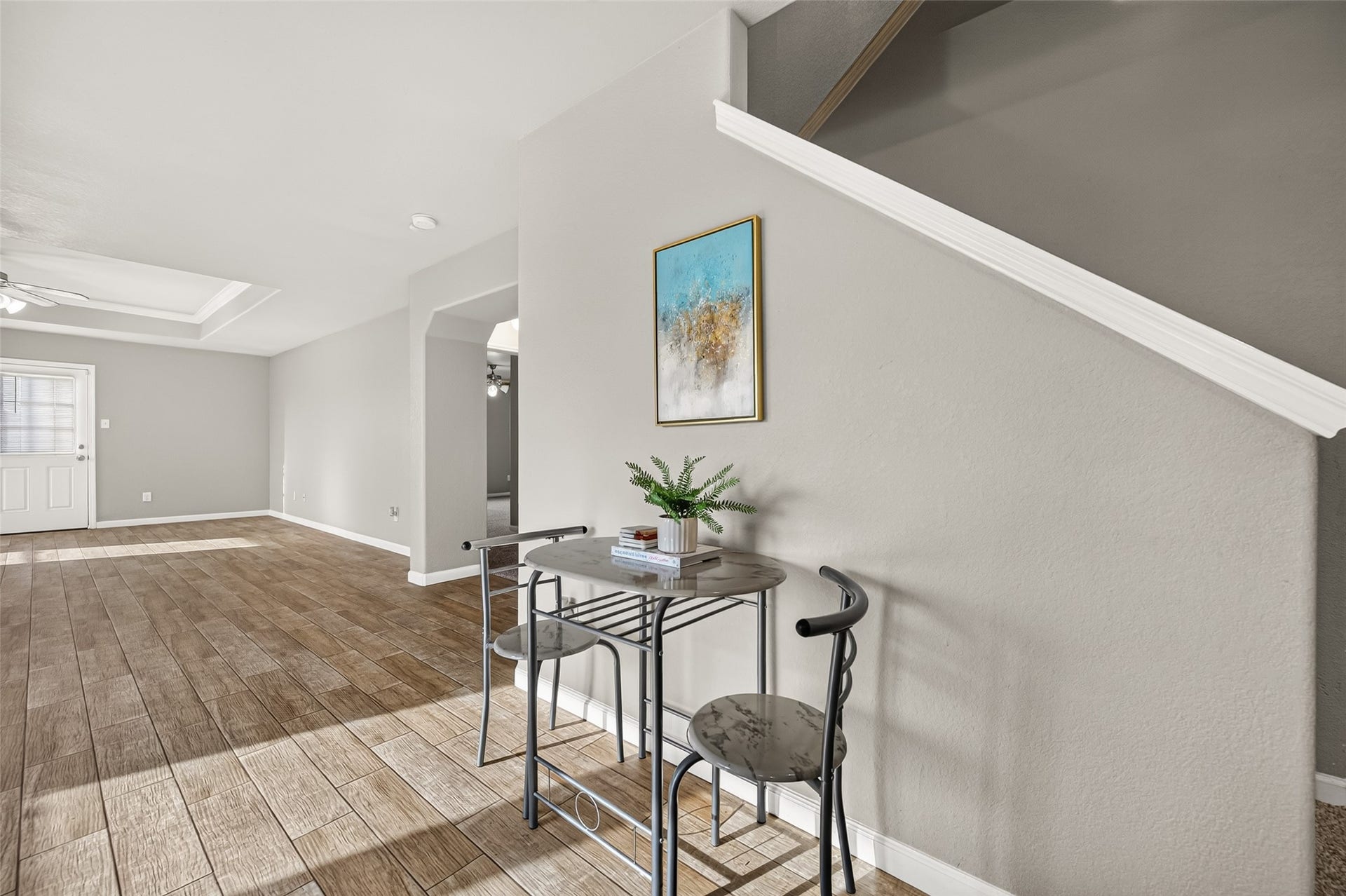19707 Dayton Springs Drive, Cypress, TX 77429 Bright and inviting open-concept living area with stylish wood-look tile flooring, modern gray walls, and a cozy breakfast nook by the staircase.