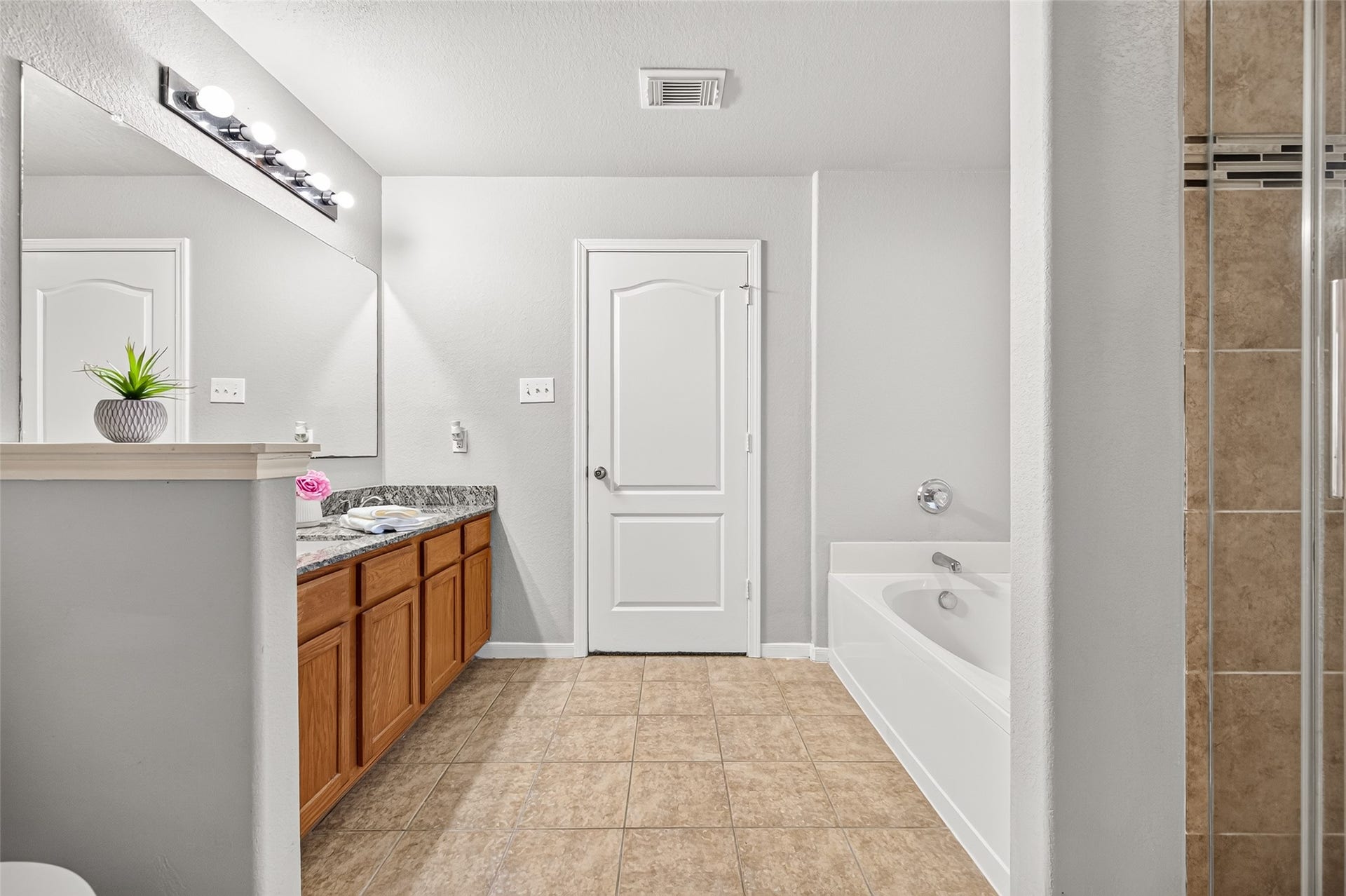 19707 Dayton Springs Drive, Cypress, TX 77429 Spacious primary bathroom featuring a large vanity with granite countertops, tile flooring, and a relaxing bathtub adjacent to a glass-enclosed shower.