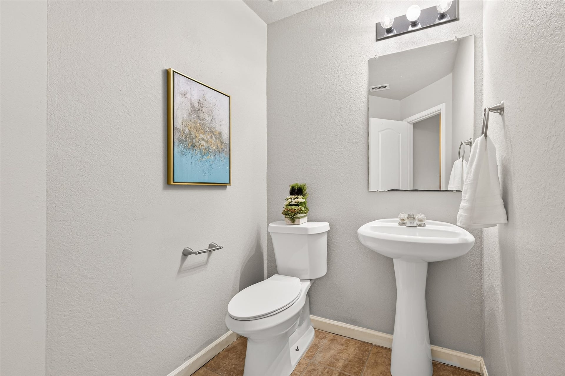 19707 Dayton Springs Drive, Cypress, TX 77429 half-bathroom on the first floor, light fixtures, featuring a pedestal sink, offering a clean and inviting space.