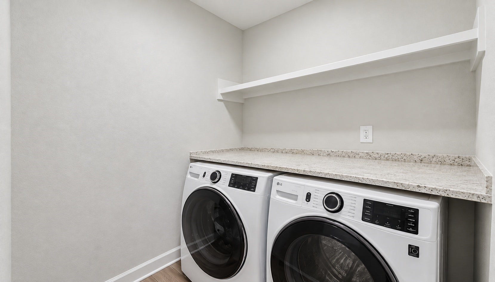 The conveniently designed laundry room offers space for a full-size washer and dryer along with shelving for additional storage and organization. Its practical layout provides a dedicated area for laundry essentials and everyday household tasks.