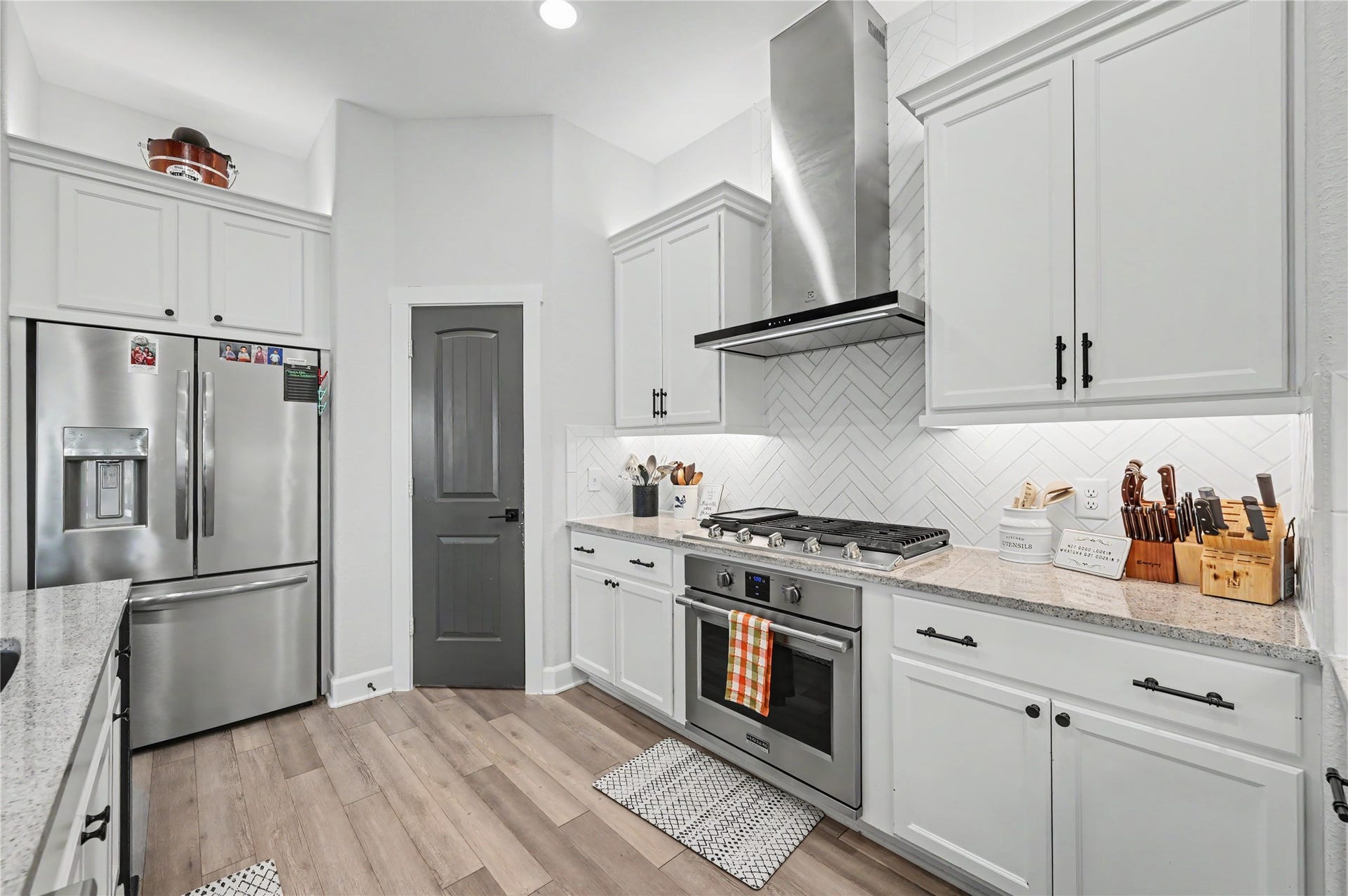 Another beautiful perspective of the kitchen showcases the stainless steel range, sleek vent hood, and ample cabinetry. The thoughtful design combines modern finishes with practical storage and workspace, creating a kitchen that's both attractive and functional.