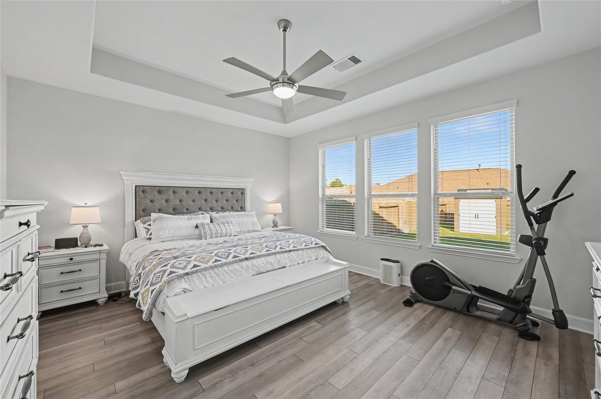 Retreat to this spacious primary bedroom featuring a beautiful tray ceiling, ceiling fan, and large windows that fill the room with natural light. The generous layout provides plenty of room for bedroom furnishings while maintaining a bright and relaxing atmosphere.