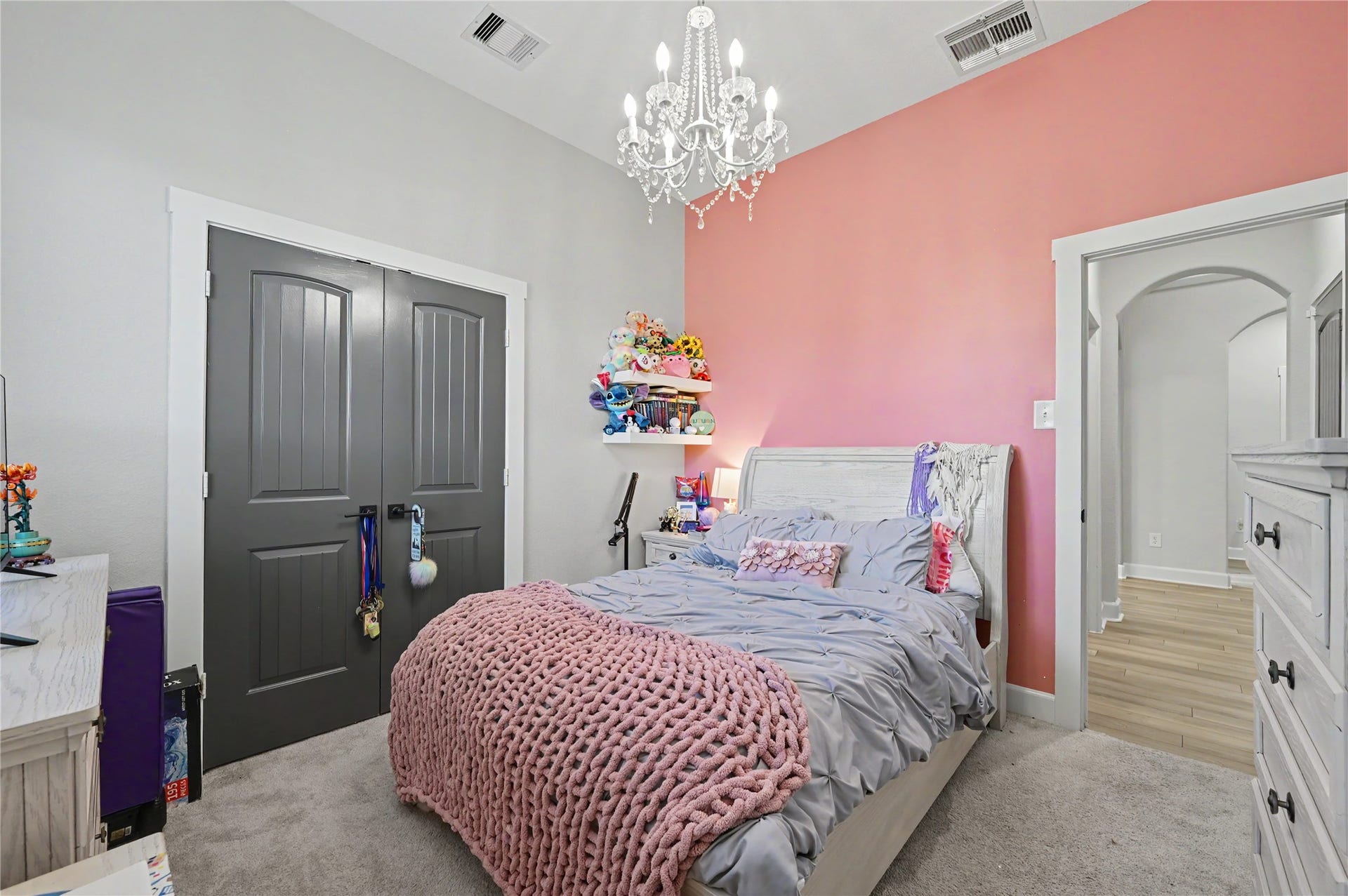 Another lovely perspective of this bedroom showcases its colorful accent wall, stylish lighting, and spacious arrangement. The room offers a cheerful atmosphere with plenty of flexibility for decorating and personalizing the space.