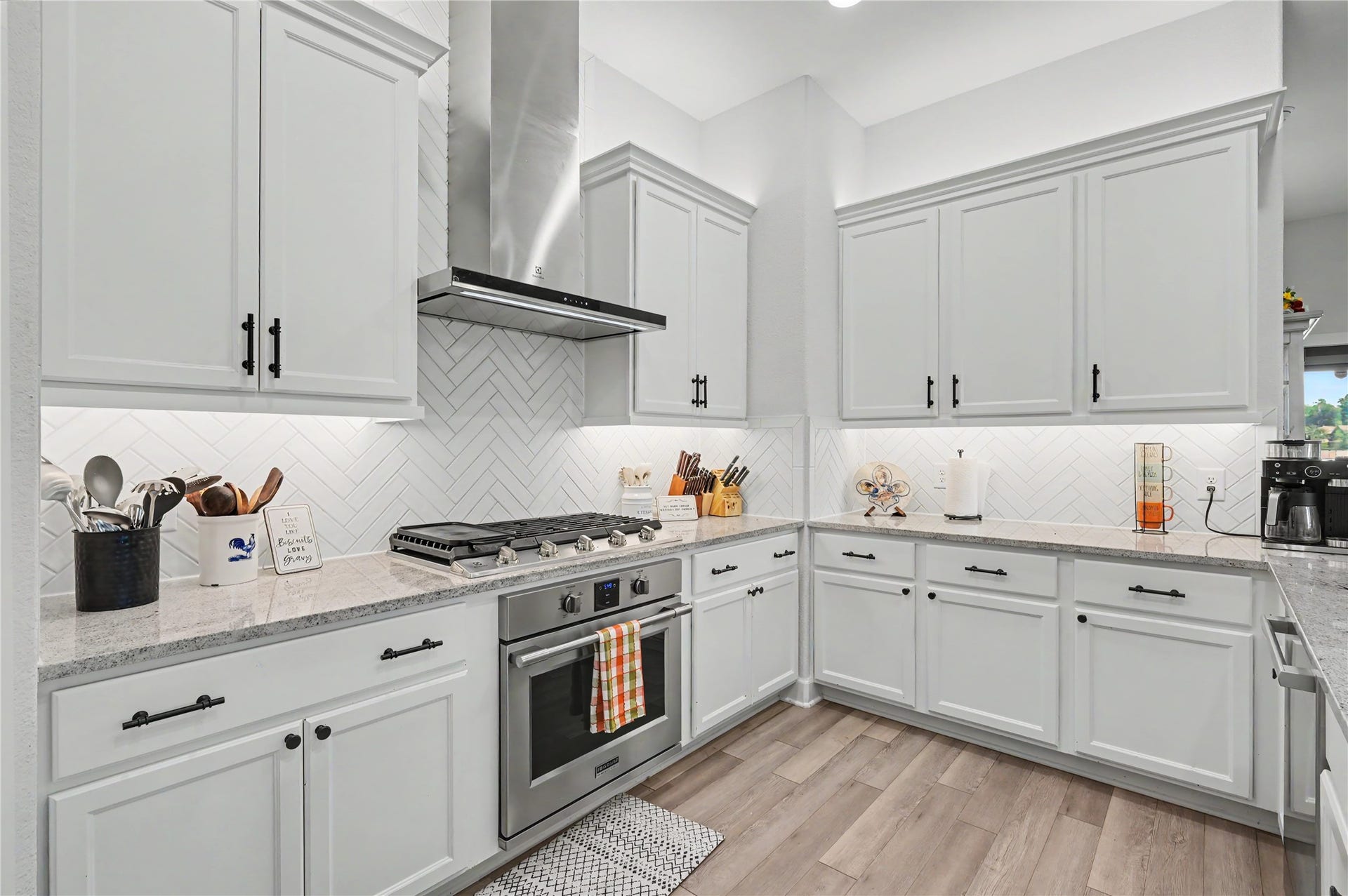 This beautifully designed kitchen features crisp white cabinetry, stainless steel appliances, and a stylish backsplash that complements the bright finishes. Generous counter space and a functional layout make meal preparation and everyday cooking a breeze.
