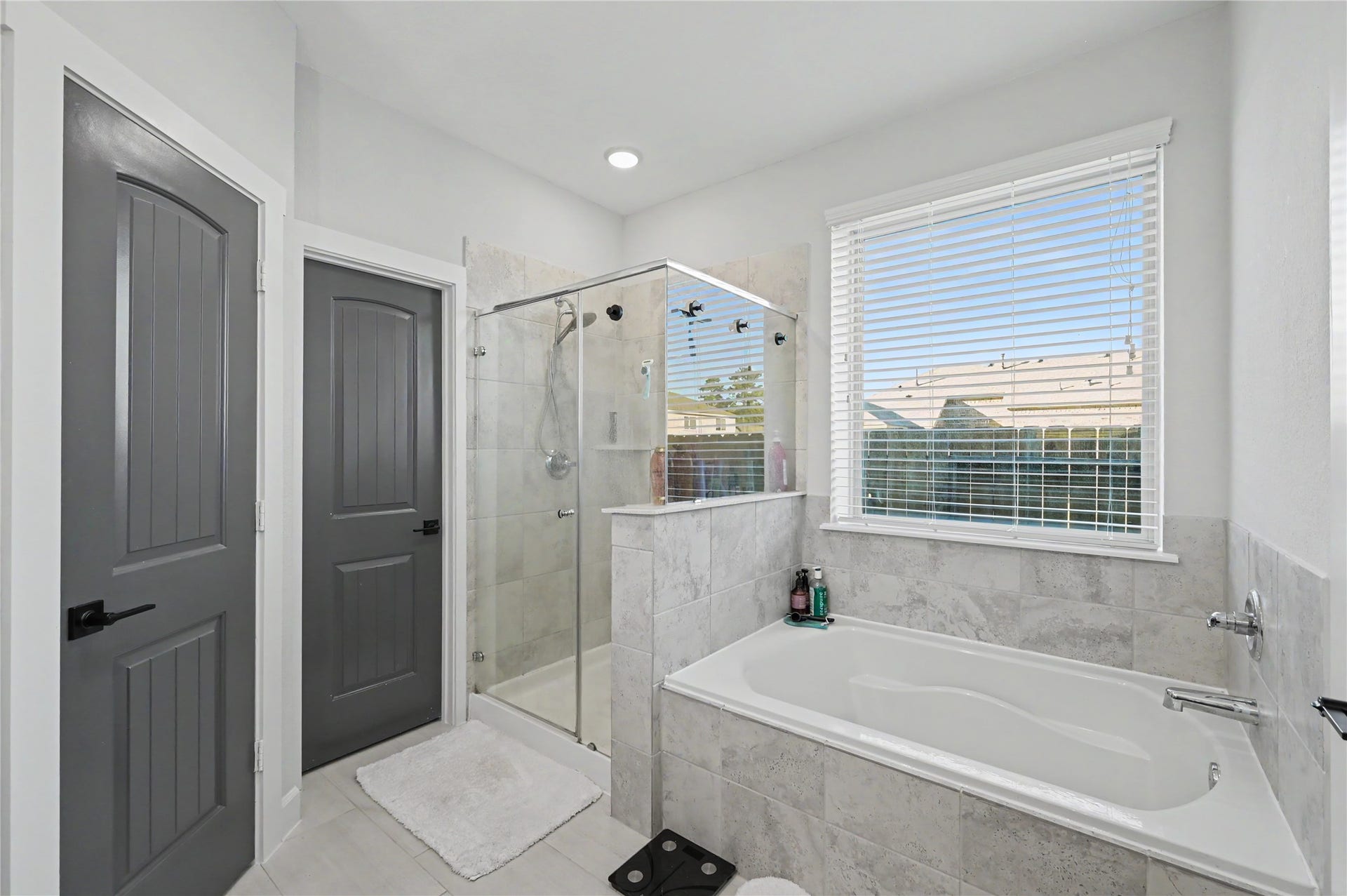 Enjoy a relaxing retreat in the primary bathroom, complete with a soaking tub positioned beneath a large window. The bright finishes, natural light, and spacious layout create an inviting atmosphere for beginning or ending your day.