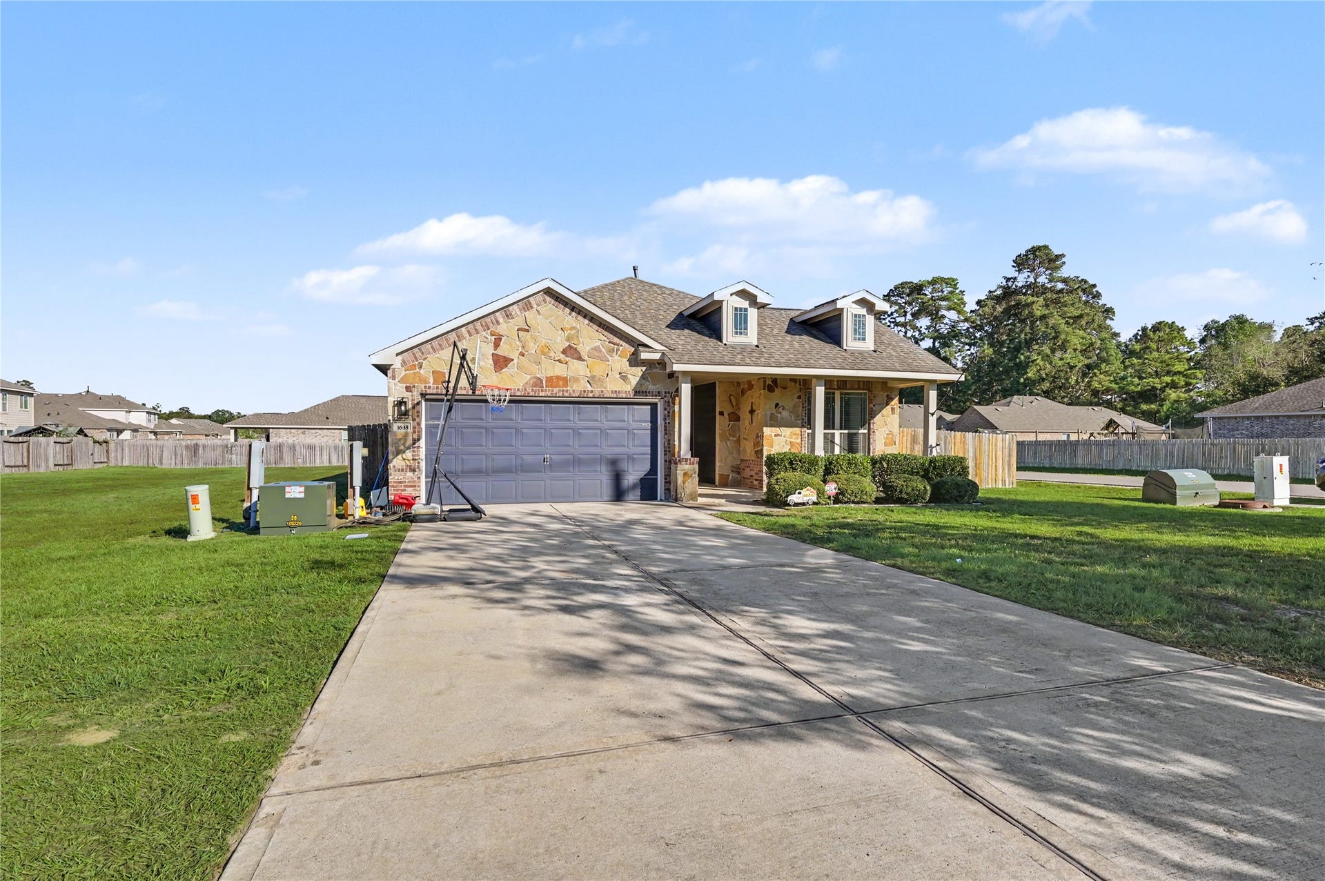 Another beautiful view of the home's welcoming exterior, featuring a spacious driveway and attractive architectural design. The combination of charming exterior finishes, landscaped surroundings, and an inviting entrance adds to the home's curb appeal.
