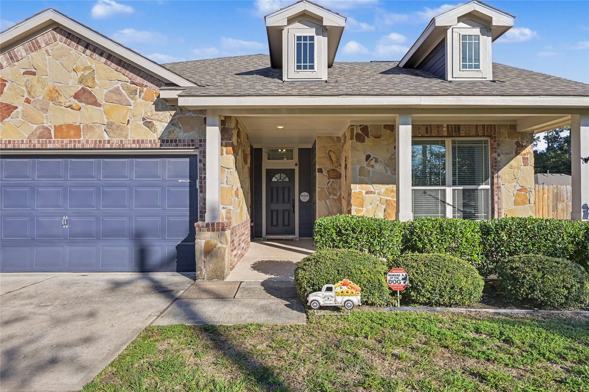 A closer look at the home's beautiful front elevation showcases attractive stone and brick detailing, a covered entryway, and thoughtfully maintained landscaping. The charming architectural details add warmth and character to the home's exterior.