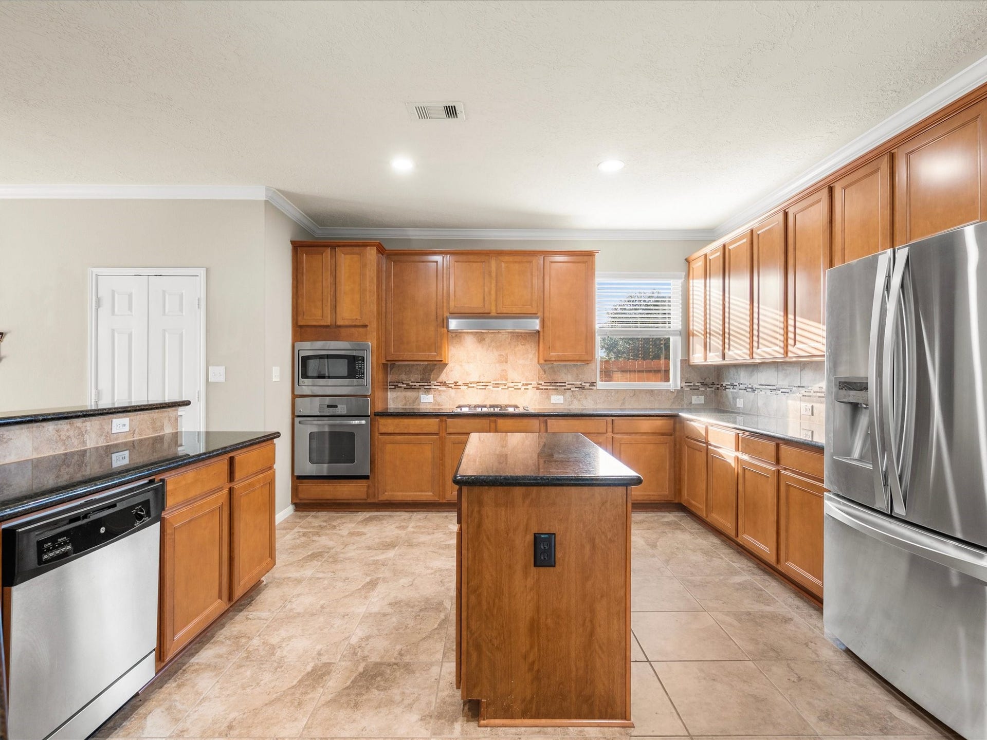 10458 Waterstone Estates Court, Tomball, TX 77375 Granite countertops, abundant cabinetry, a center island, stainless steel appliances, and a gas cooktop combine with pantry storage and generous natural light to create a spacious, well-appointed kitchen.